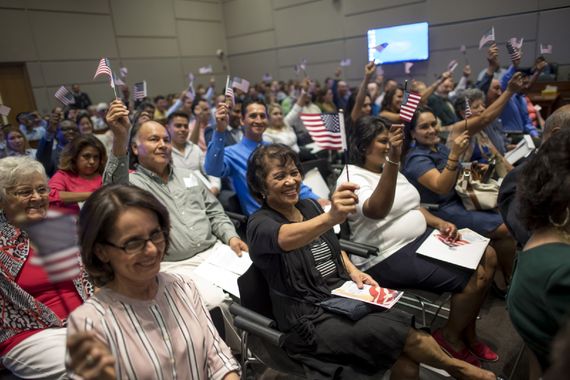 New U.S. citizens wave American flags during a naturalization ceremony at the Evo A. DeConcini U.S. Courthouse in Tucson, Ariz., on Sept. 16, 2016. MUST CREDIT: Bloomberg photo by David Paul Morris