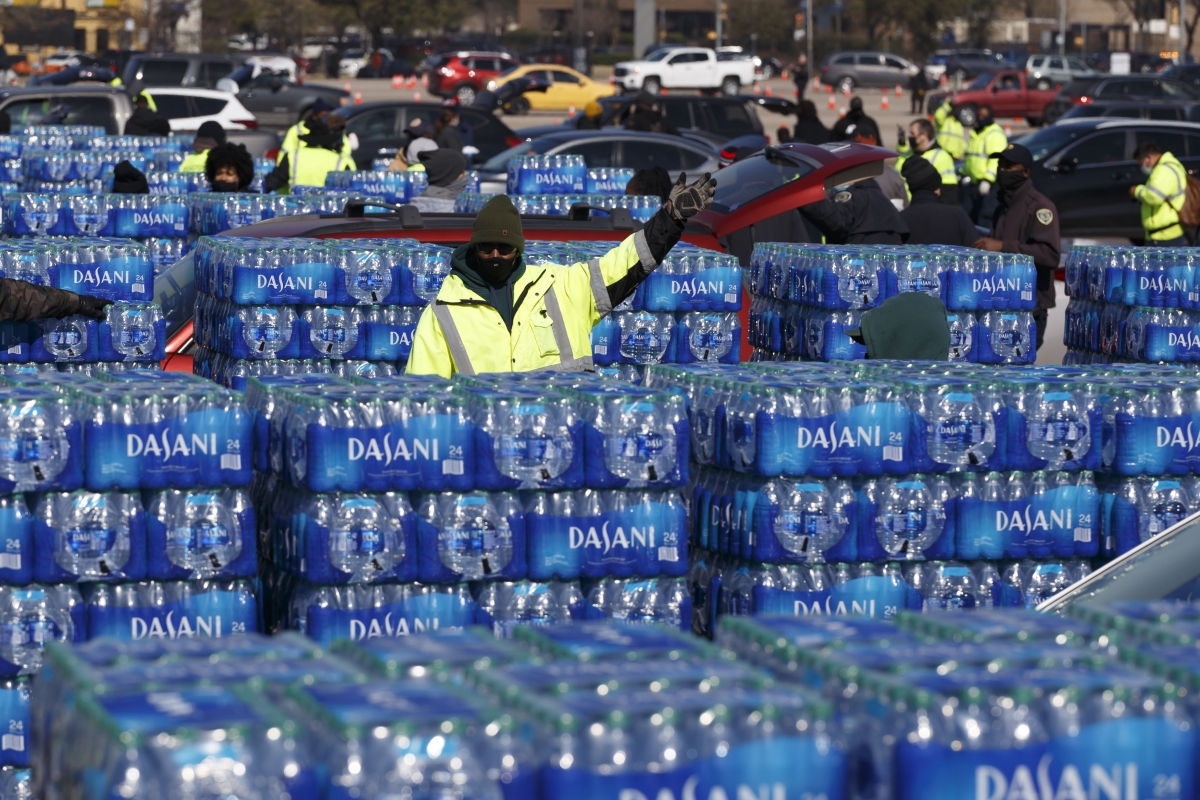 Houston city workers direct lines of cars waiting to receive bottled water at a high school sports complex. Houston, the nation's fourth-largest city, was under a boil-water advisory Friday, as more than 14 million Texans were still experiencing water-service disruptions. Photo by Michael Stravato for The Washington Post