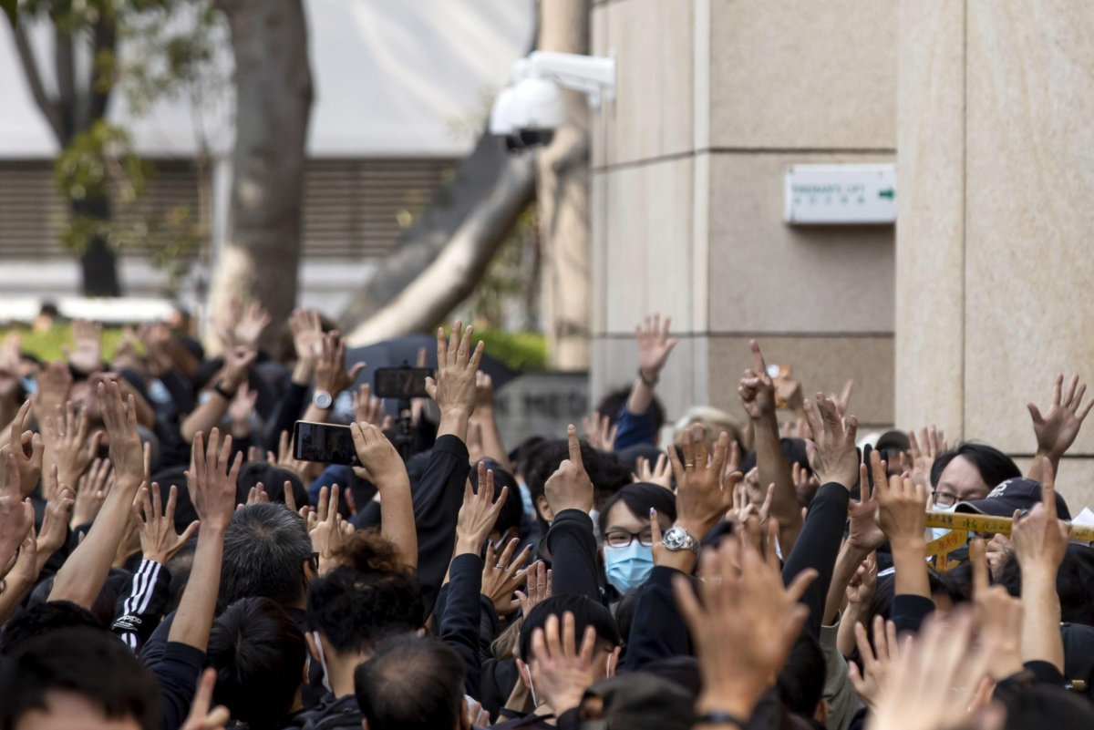 Pro-democracy demonstrators make the gesture for the "Five demands, not one less" motto outside the West Kowloon Magistrates Courts in Hong Kong on March 1, 2021. MUST CREDIT: Bloomberg photo by Paul Yeung