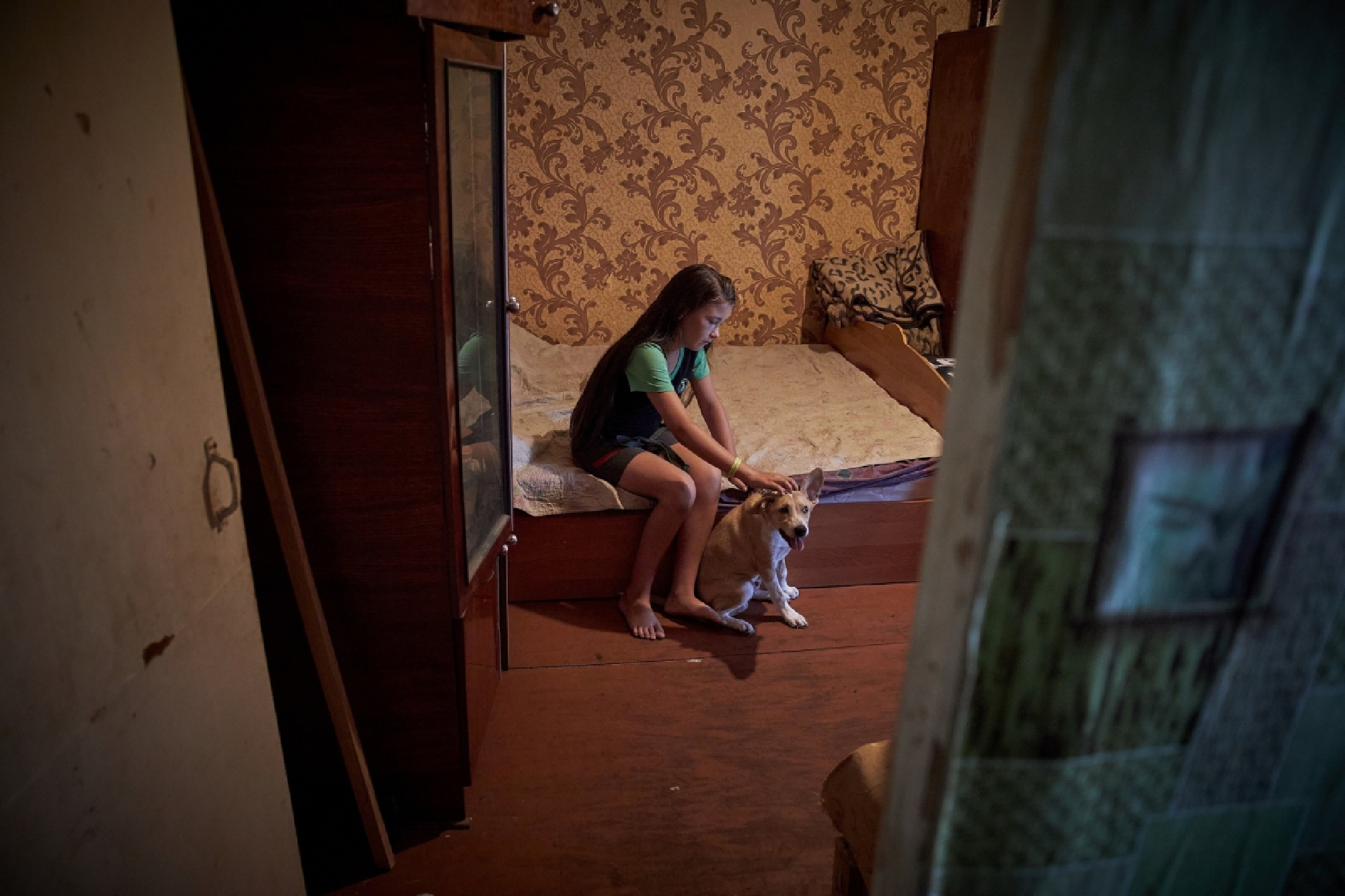 On 7 August 2020, a girl plays with her dog during a visit by social worker Iryna Laposhyna (not pictured) to meet with his family in the village of Soledarskahromada, Eastern Ukraine. Iryna works with nine families in the village. During the quarantine in place to stem the spread of COVID-19, she has been providing psychological help as well as in-kind assistance such as providing food and hygiene items and helping to obtain government benefits. © UNICEF/UNI359075/Zmey