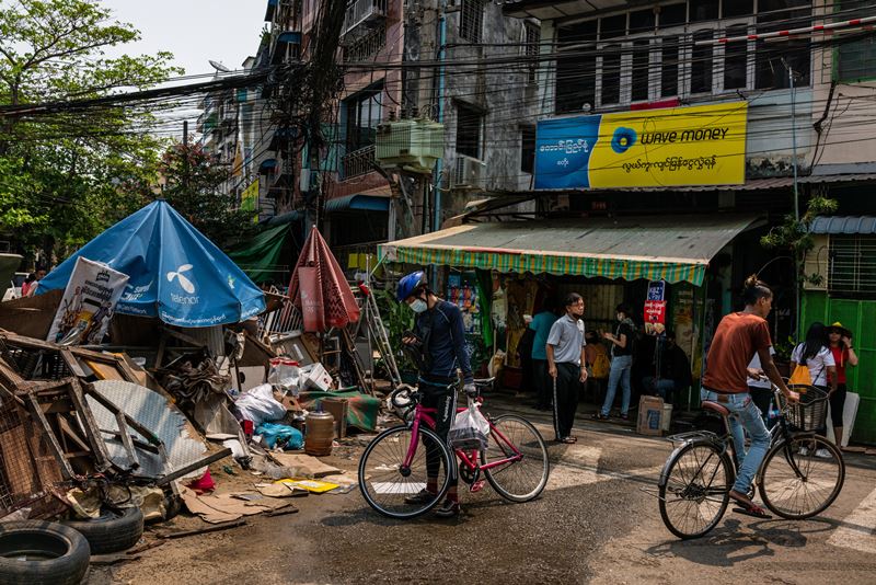 A food delivery employee checks his phone after encountering a barricade in the Sanchaung neighborhood of Yangon. The neighborhood has emerged as the heart of the anti-coup resistance. MUST CREDIT: photo for The Washington Post.