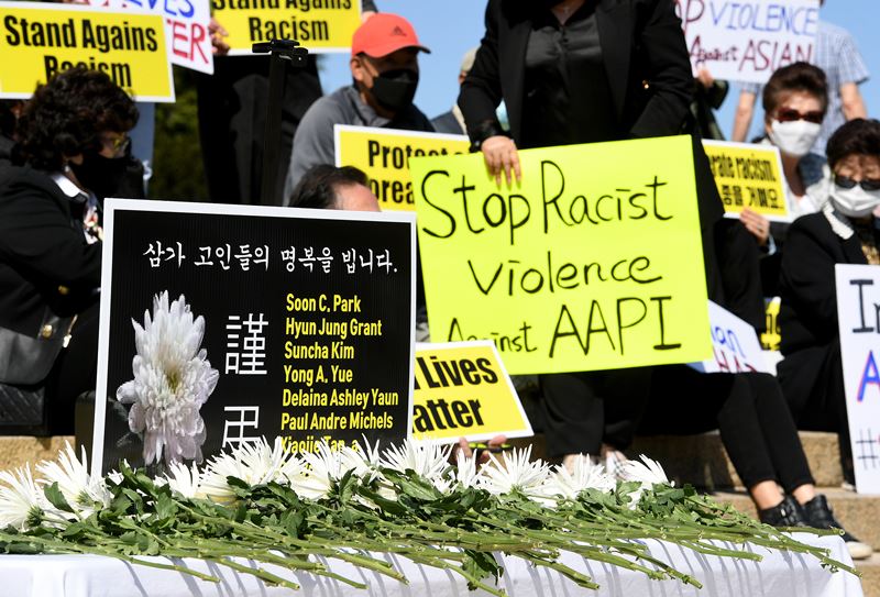 Flowers are placed Saturday, March 27, 2021, at the Lincoln Memorial in front of a sign with the names of the Atlanta shooting victims as people hold up signs protesting violence against Asians. MUST CREDIT: Photo by Will Newton for The Washington Post