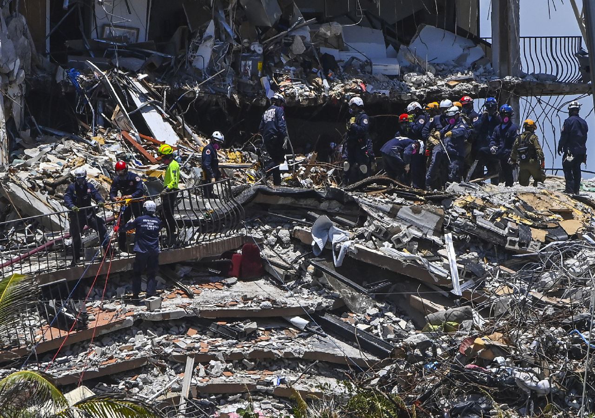 Rescue crew members search through rubble at Champlain Towers South. MUST CREDIT: Washington Post photo by Ricky Carioti.