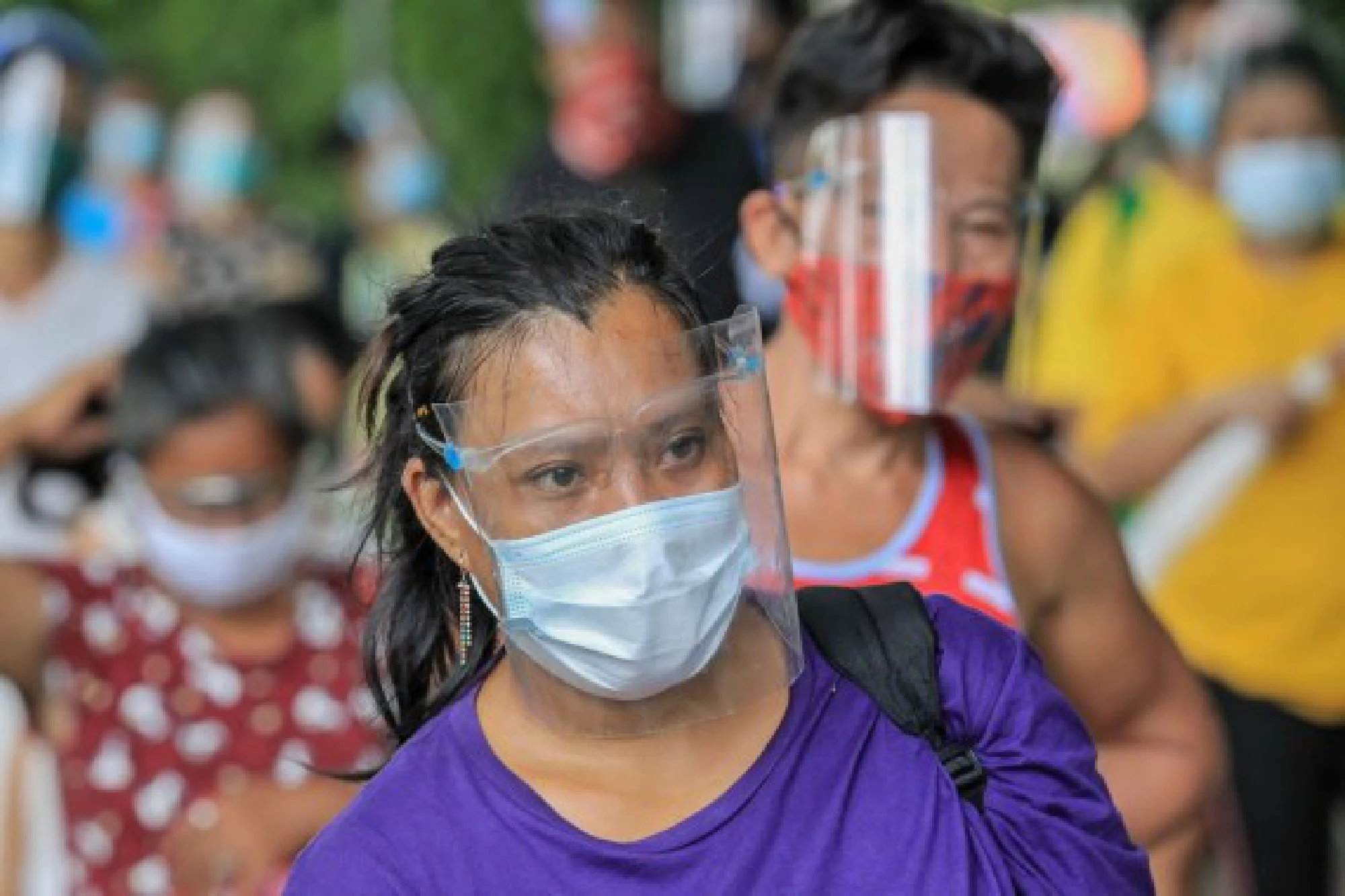 Residents wearing protective masks are seen as they line up for free goods from a community pantry in Manila, the Philippines
