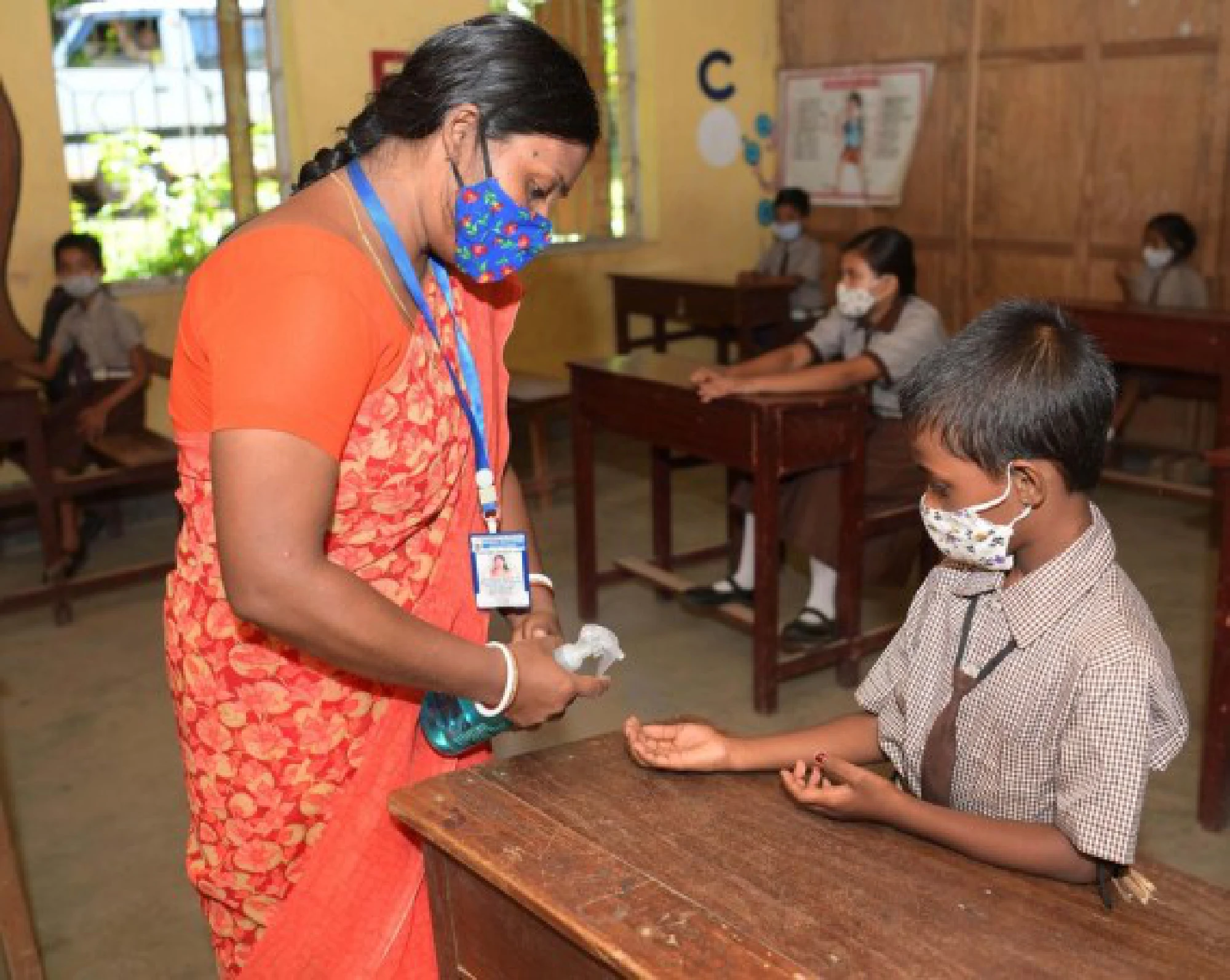 A teacher sanitizes the hands of a student at school in Agartala, the capital city of India's northeastern state of Tripura