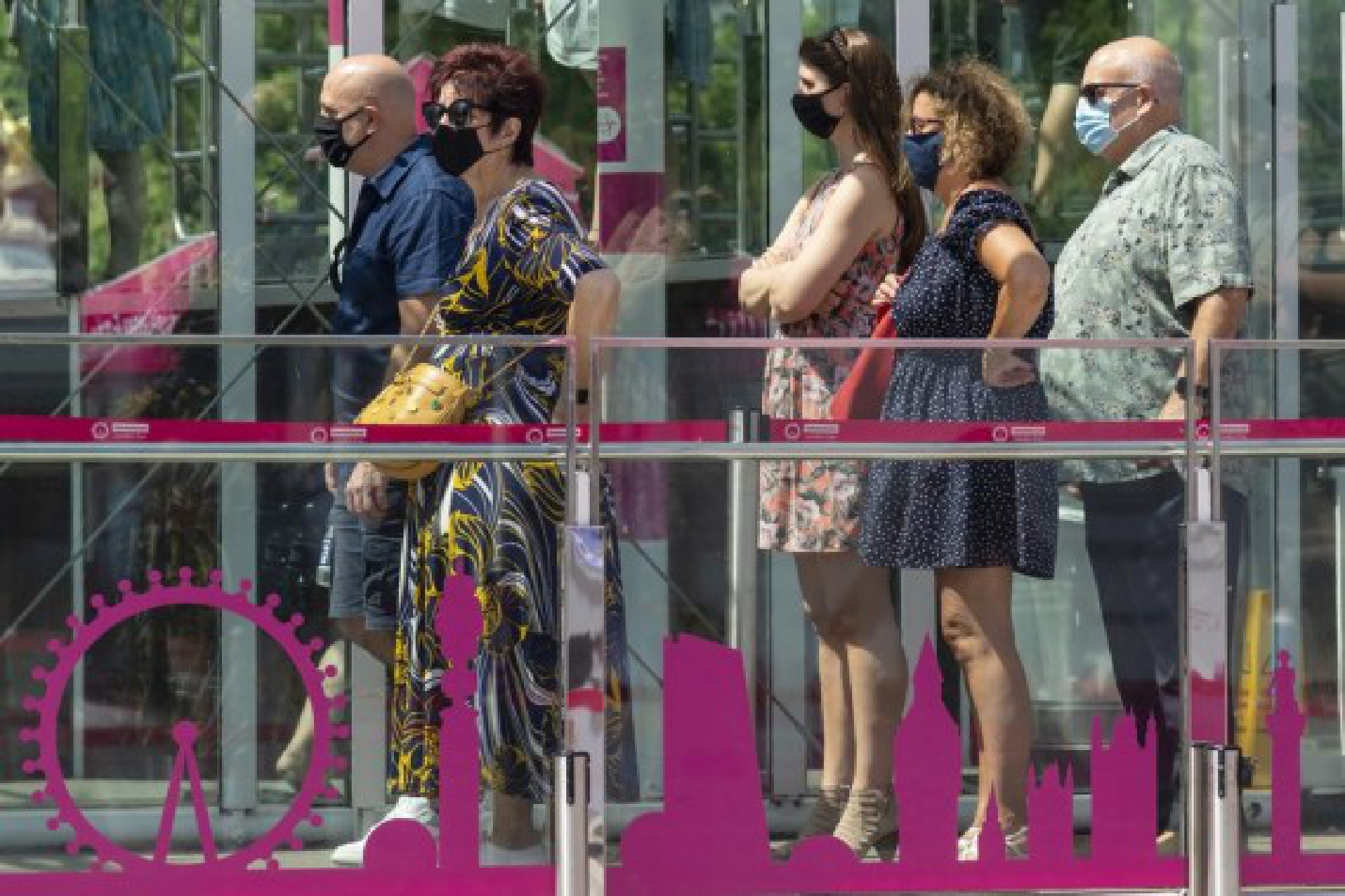 Visitors wearing face masks queue to board the London Eye in London, Britain