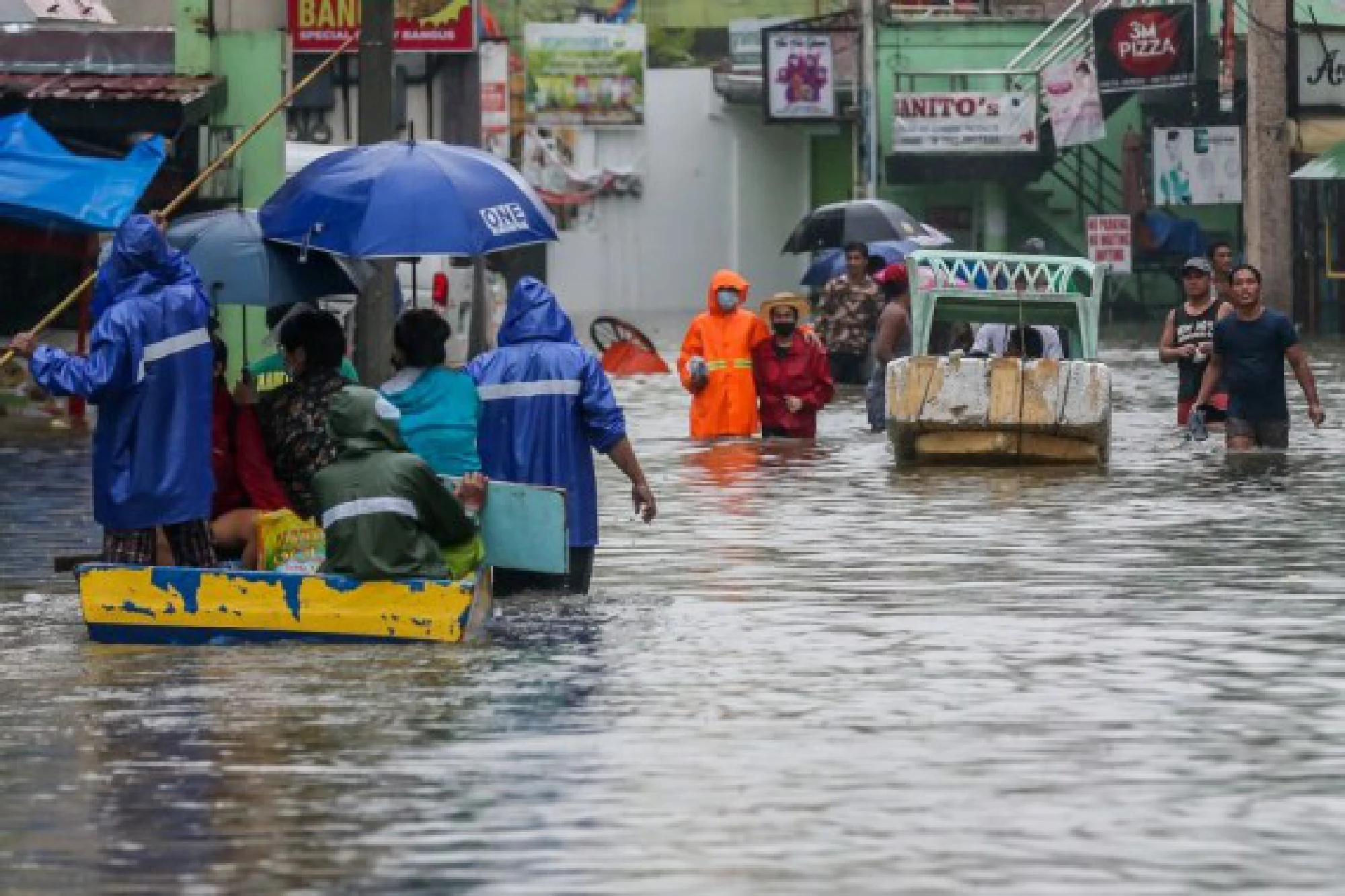 People wade through the flood water brought by heavy monsoon rains in Rizal Province, the Philippines, July 24, 2021.