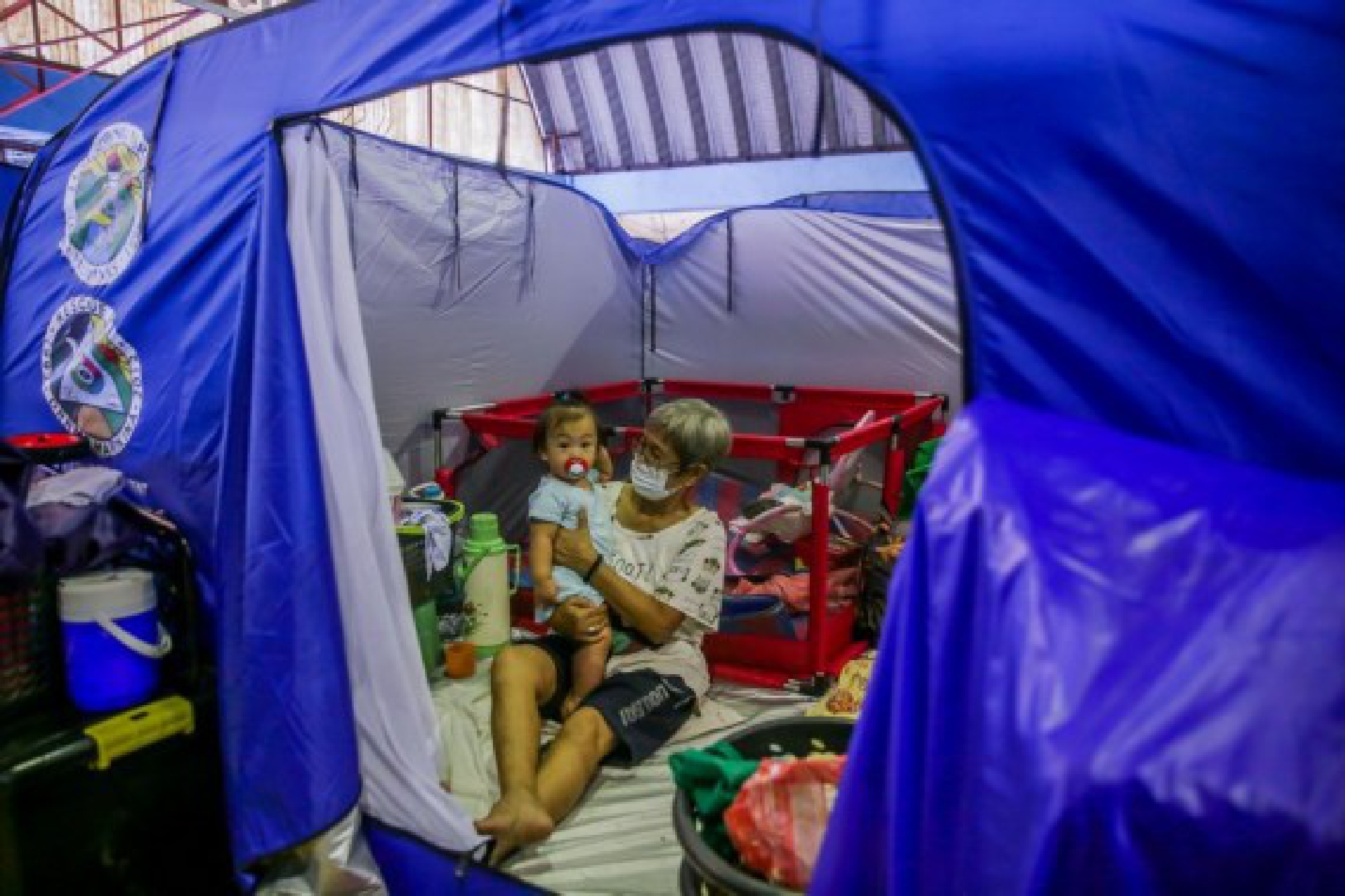 A grandmother takes care of her grandchild inside an emergency modular tent as they take shelter at an evacuation center in Marikina City, the Philippines on July 24, 2021.