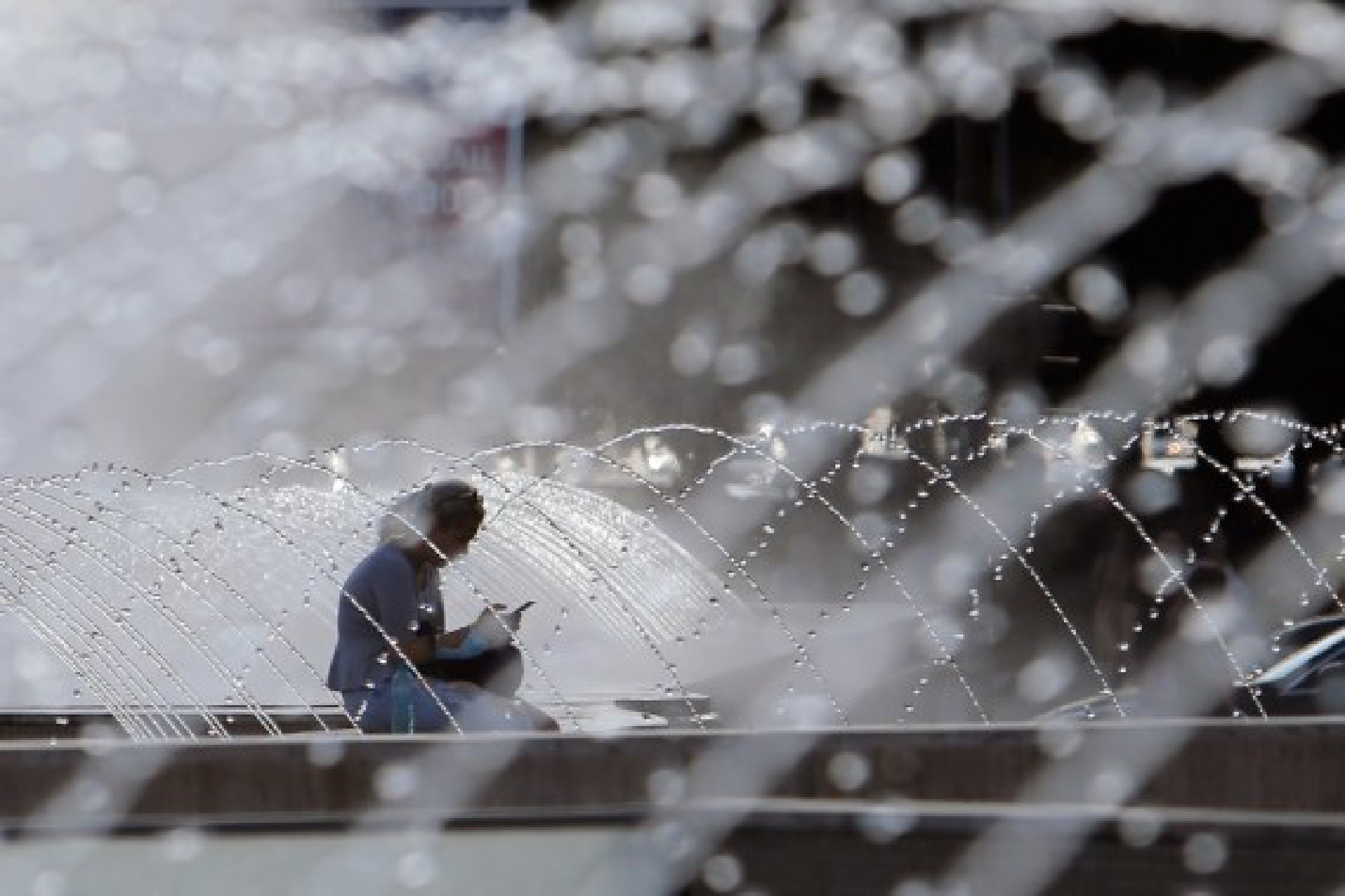 A woman sits near a fountain during a hot day in downtown Bucharest, Romania, on July 28, 2021.