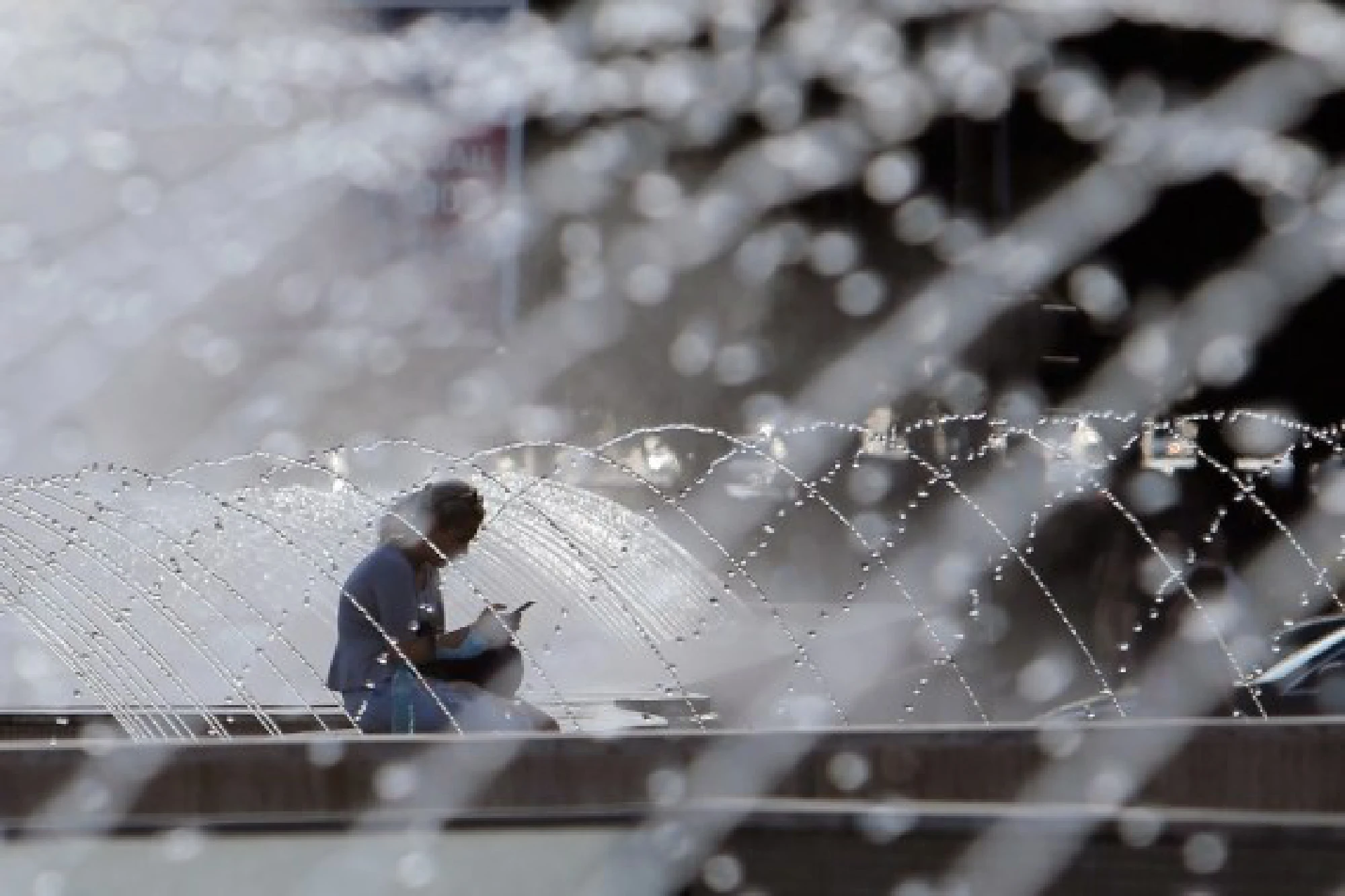 A woman sits near a fountain during a hot day in downtown Bucharest, Romania, on July 28, 2021.