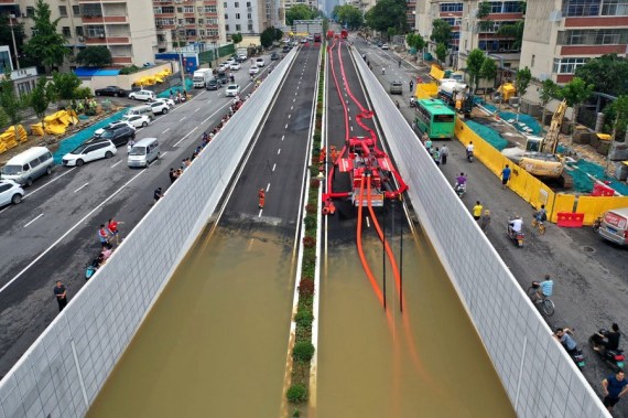 In this aerial photo, firefighters pump rainwater out of a road in Zhengzhou, capital of central China's Henan Province