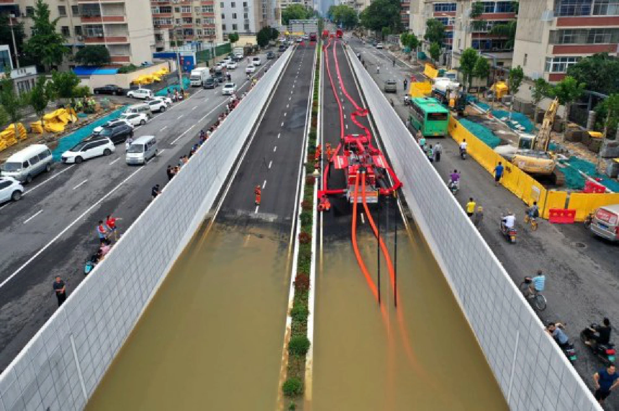 In this aerial photo, firefighters pump rainwater out of a road in Zhengzhou, capital of central China's Henan Province
