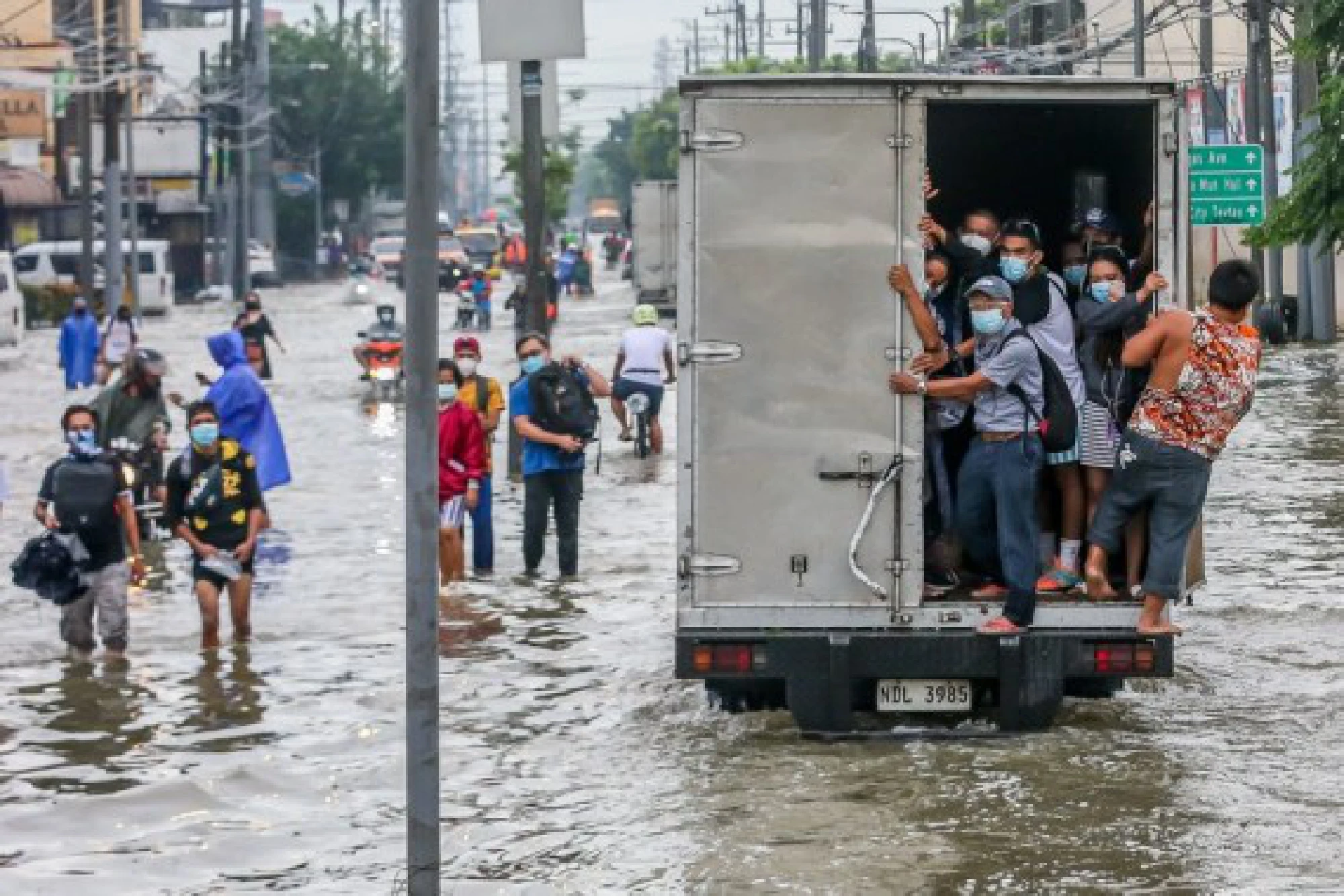 People wade through the flood water brought by heavy monsoon rains in Rizal Province, the Philippines, July 24, 2021.