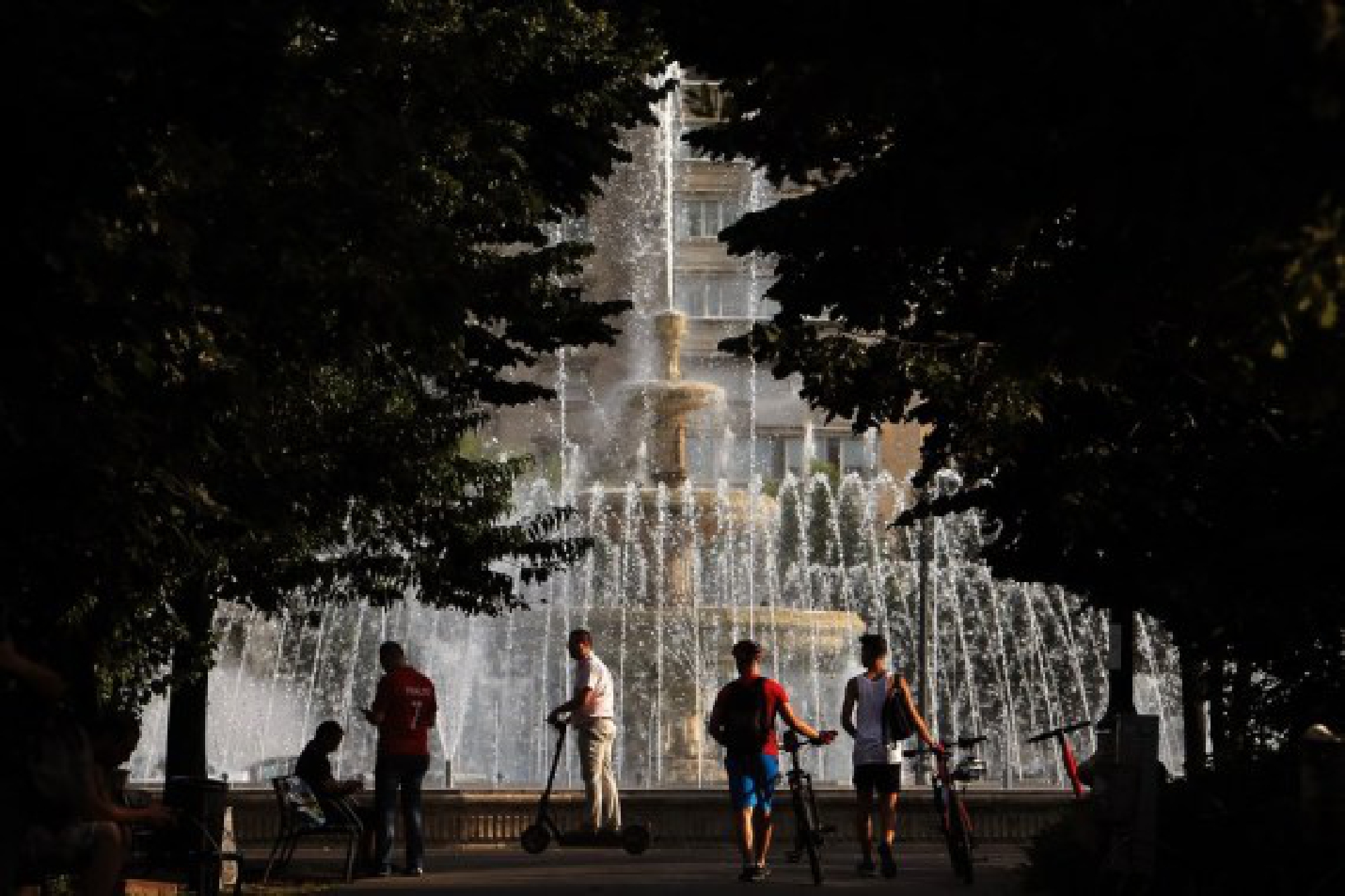 People are seen beside a fountain during a hot day in downtown Bucharest, Romania, on July 28, 2021.