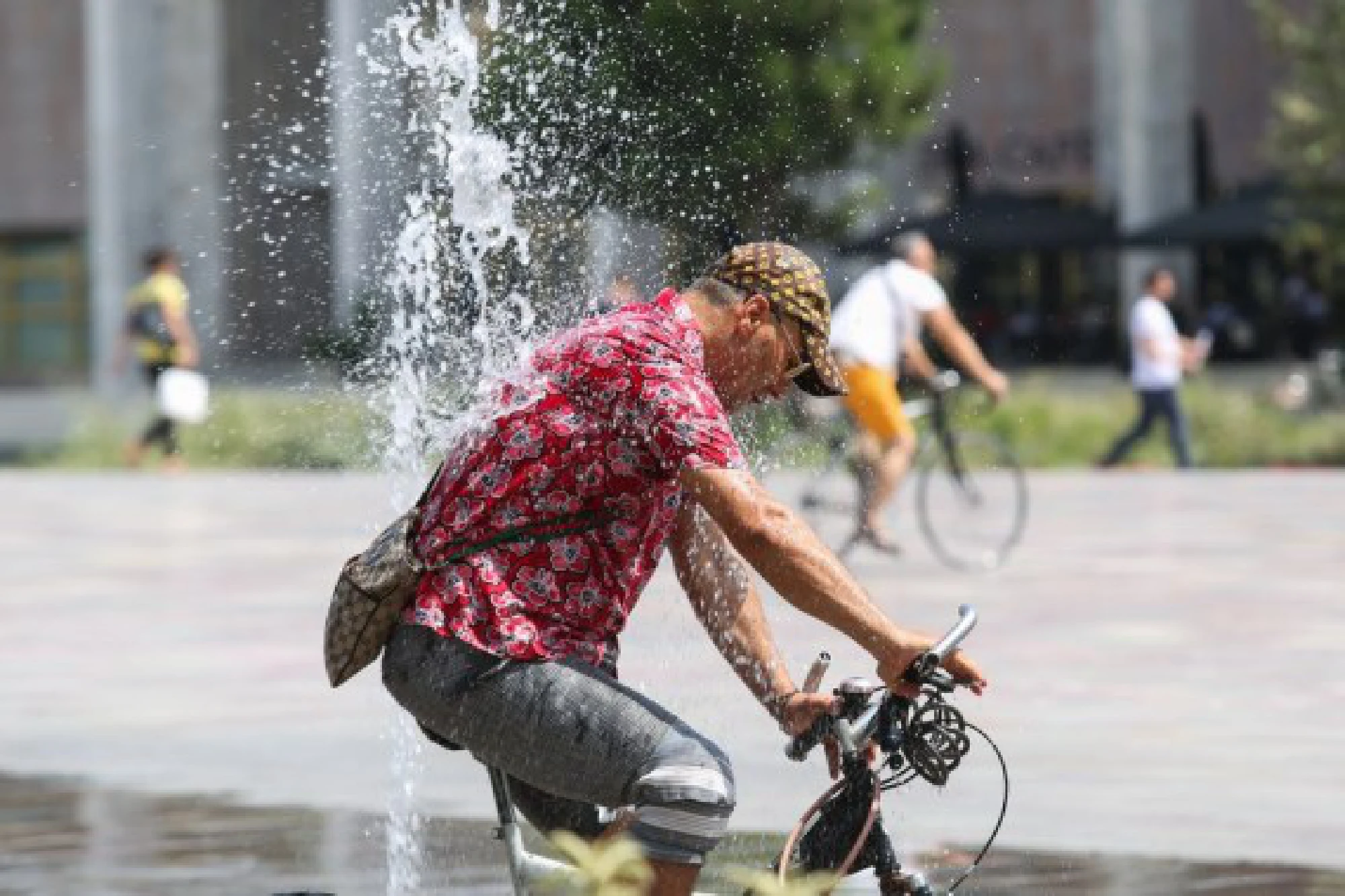 A man rides a bicycle through fountains at Skanderbeg Square in the center of capital Tirana, Albania, July 29, 2021.