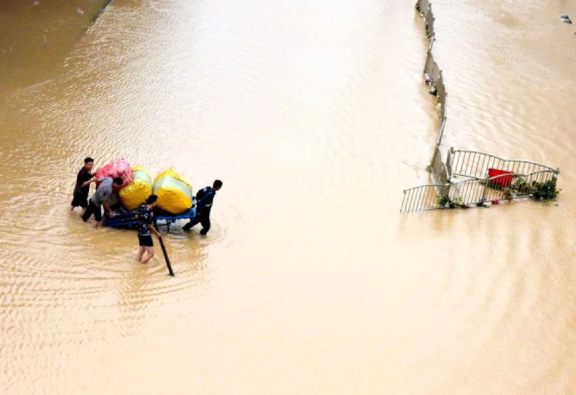 Citizens transport their property on a flooded street in Zhengzhou, central China's Henan Province