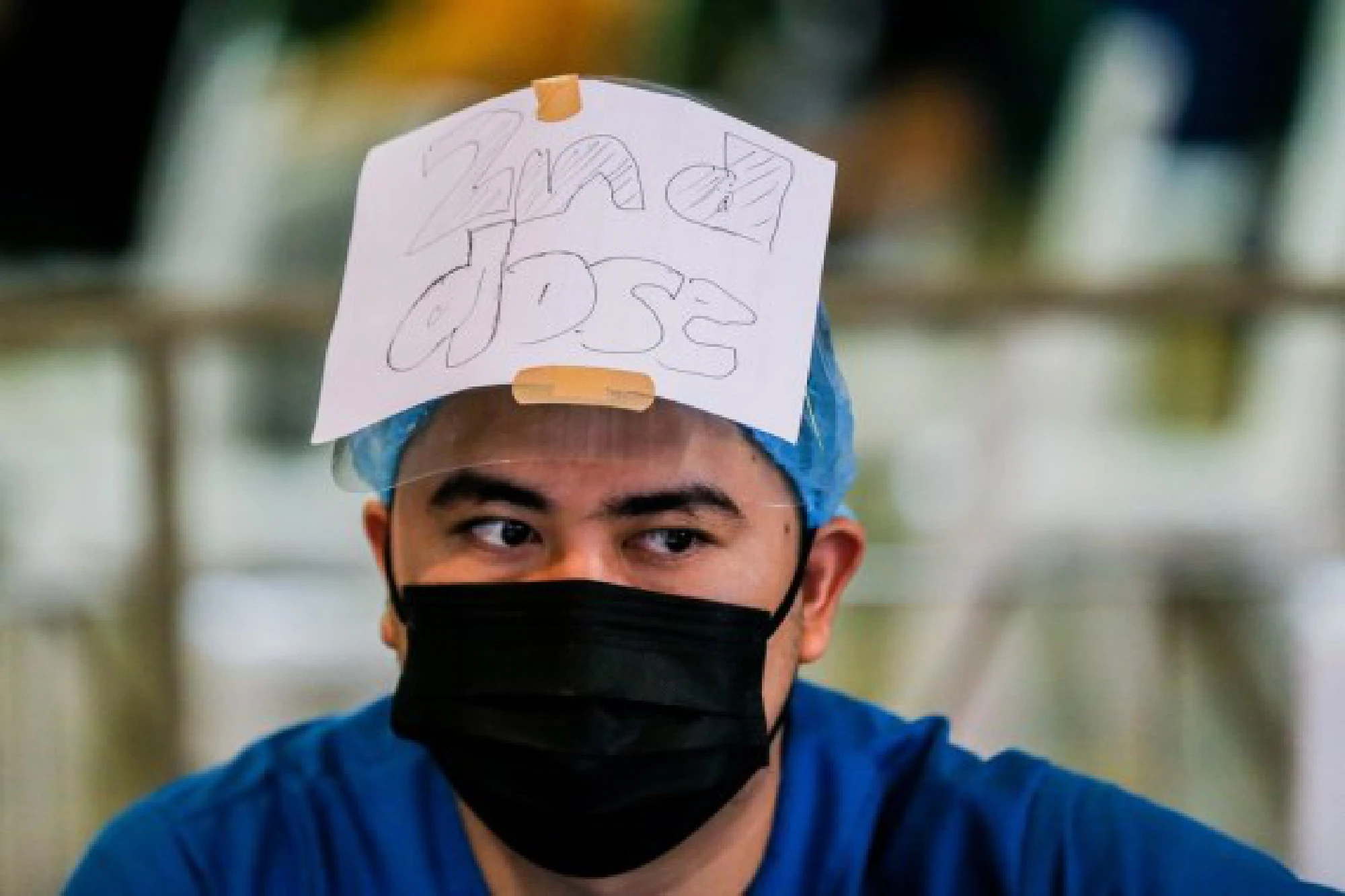 A health care worker wears a sign that reads &quot;2nd dose&quot; on his head to guide people getting inoculated with the Sinovac COVID-19 vaccine at a school turned into a vaccination site in San Juan City, the Philippines 