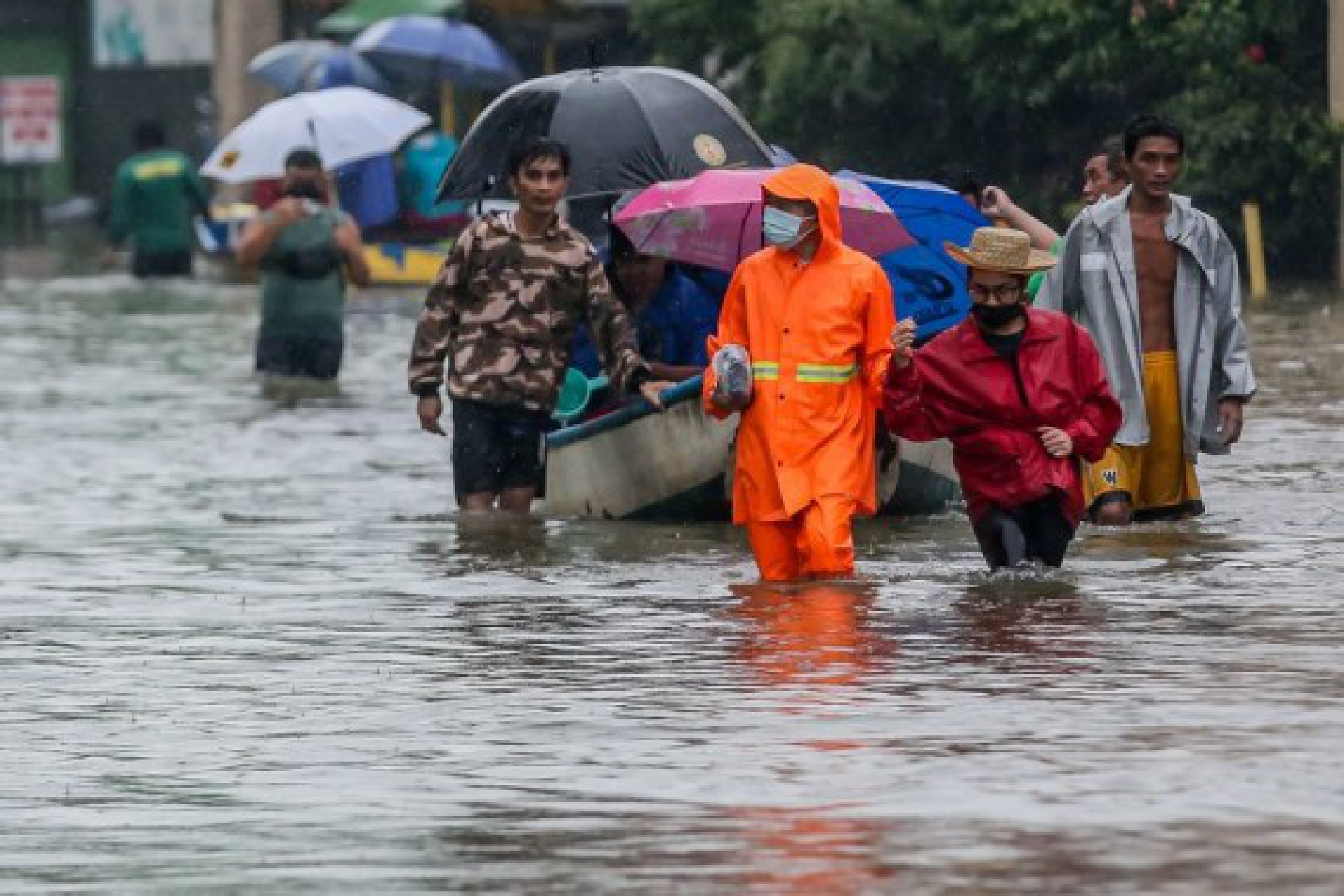 People wade through the flood water brought by heavy monsoon rains in Rizal Province, the Philippines, July 24, 2021.