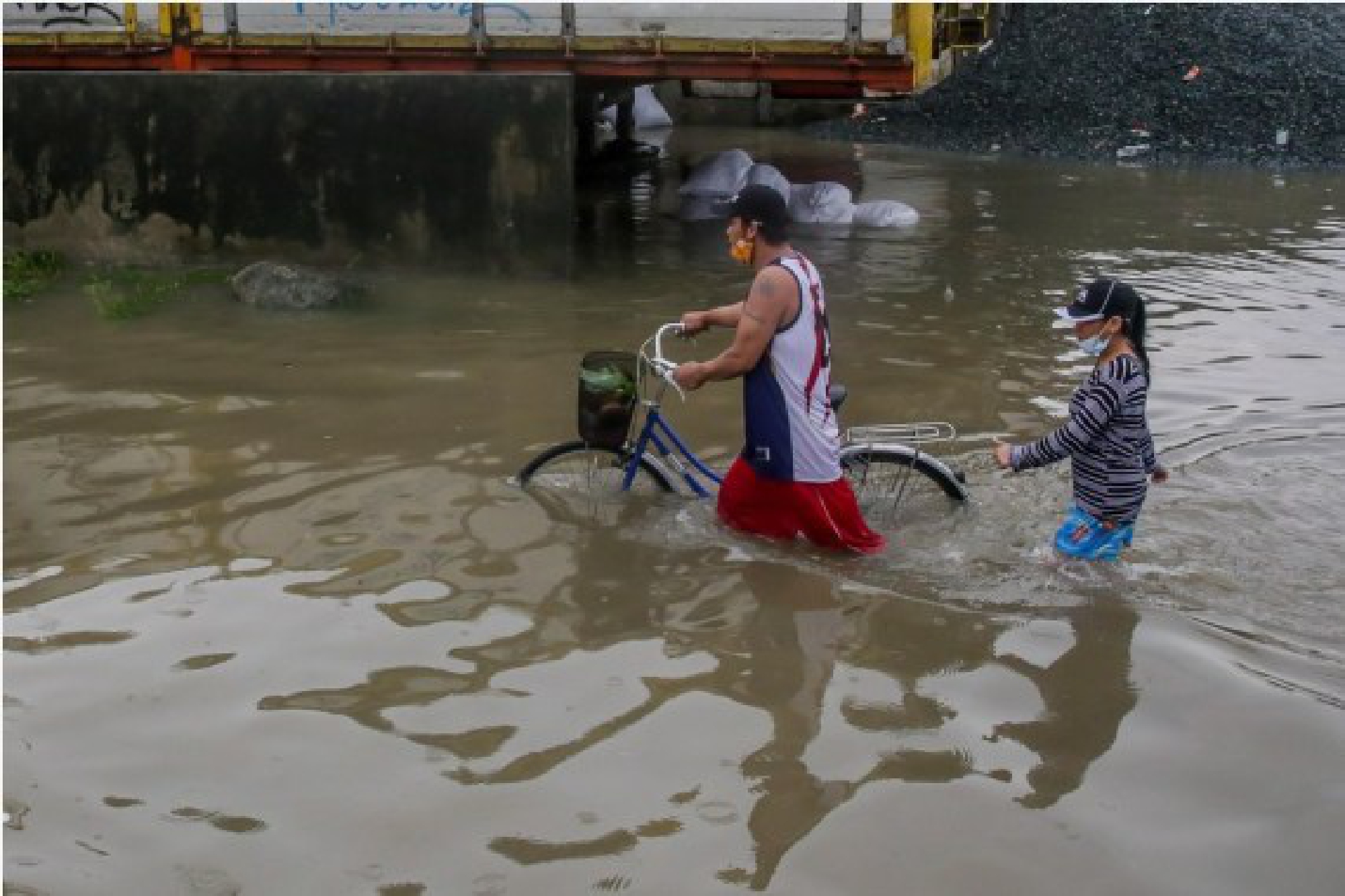 People wade through the flood water brought by heavy monsoon rains in Rizal Province, the Philippines, July 24, 2021.