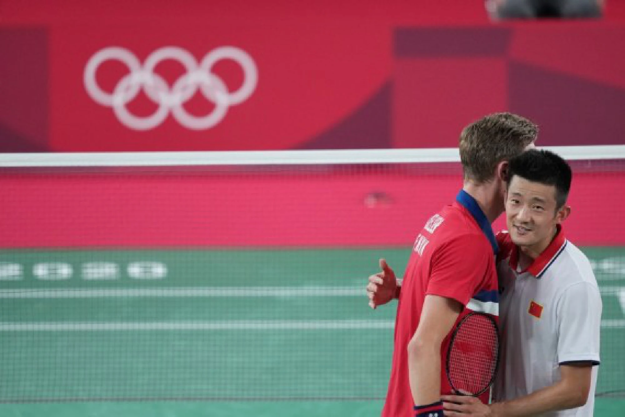Viktor Axelsen (L) of Denmark embraces Chen Long of China after their men's singles badminton final on Aug. 2, 2021.