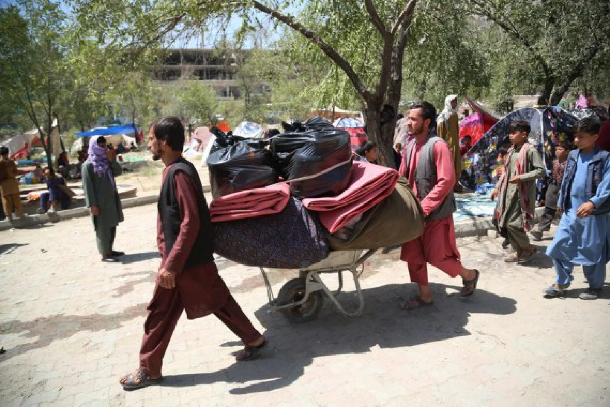Afghan displaced people who fled from their homes during the fights carry their belongings in a public park in Kabul, Afghanistan, Aug. 11, 2021.