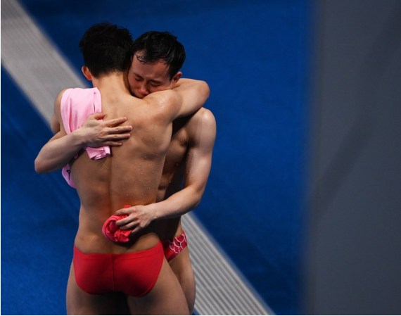 Xie Siyi (Rear) and Wang Zongyuan of China hug each other after the men's 3m springboard final of diving at the Tokyo 2020 Olympic Games in Tokyo, Japan, Aug. 3, 2021. 