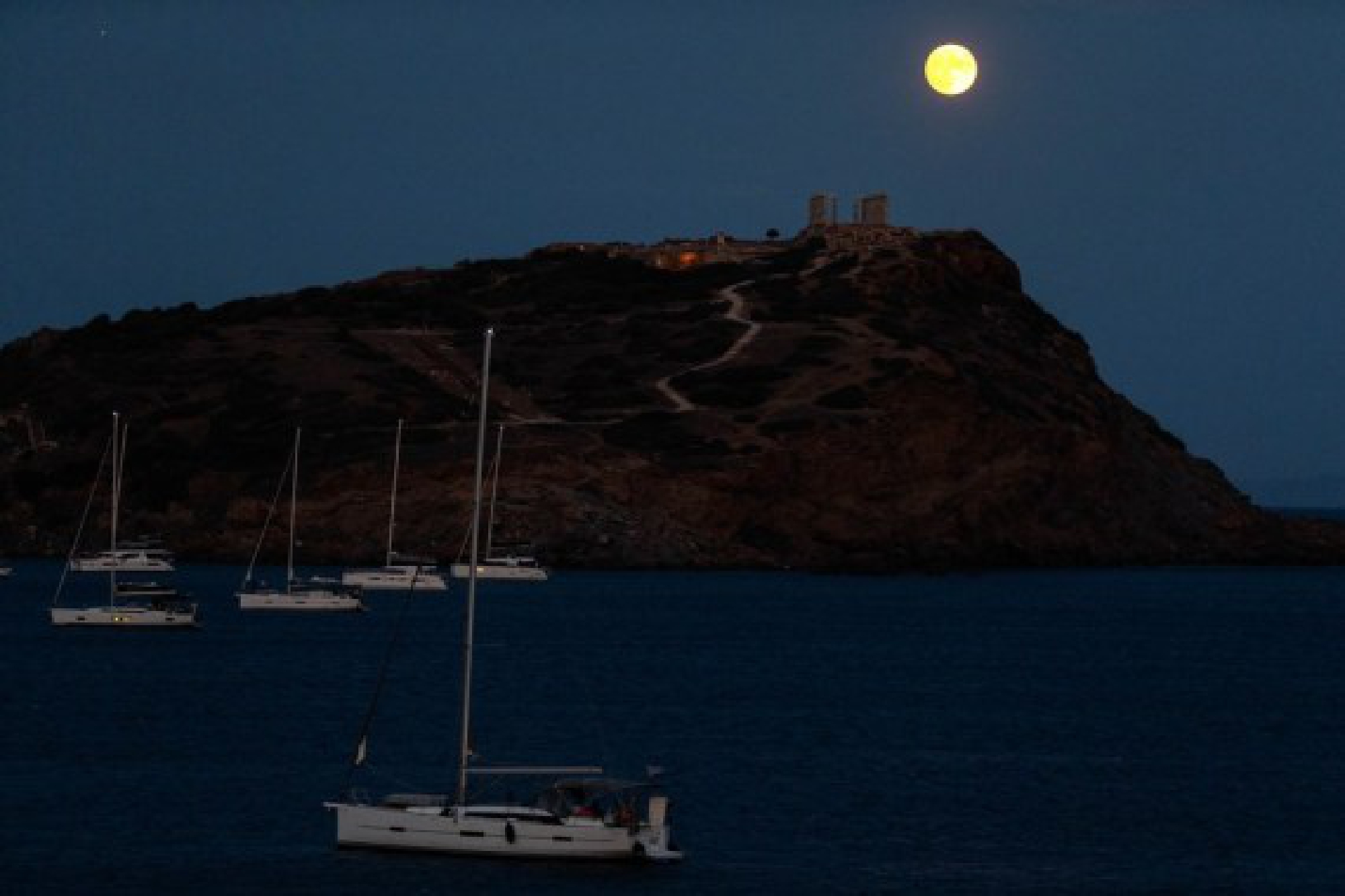 A full moon is seen over the Temple of Poseidon at cape Sounion, some 70 km southeast of Athens, Greece, on Aug. 21, 2021.