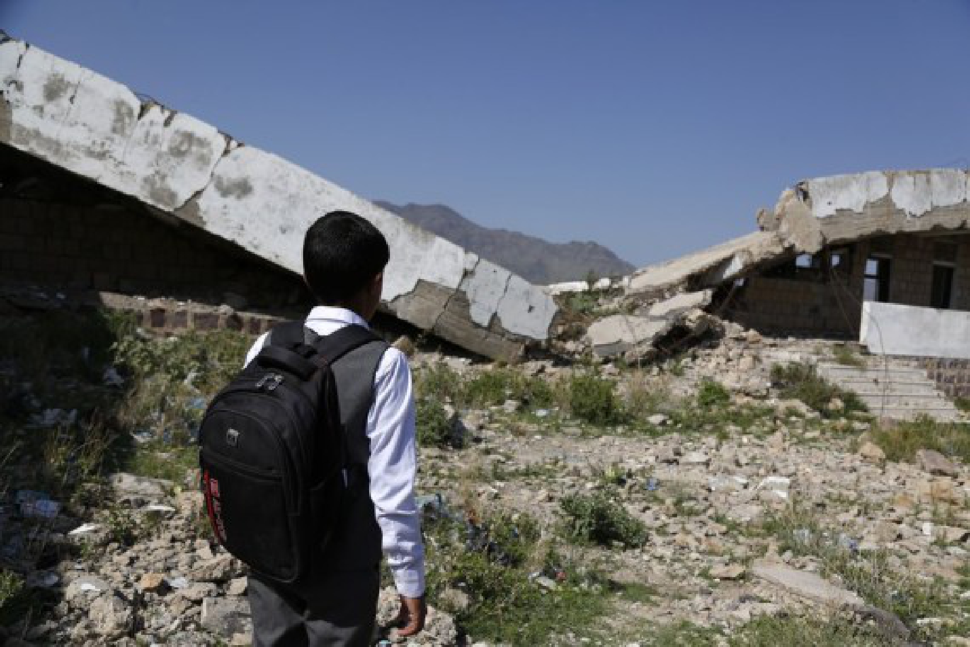 A child is standing in front of a half-collapsed teaching building at Shuhada-Alwahdah school in Al-Radhmah district in Ibb province, about 190 km south of the Houthi-held capital Sanaa, Yemen, on Aug. 14, 2021.