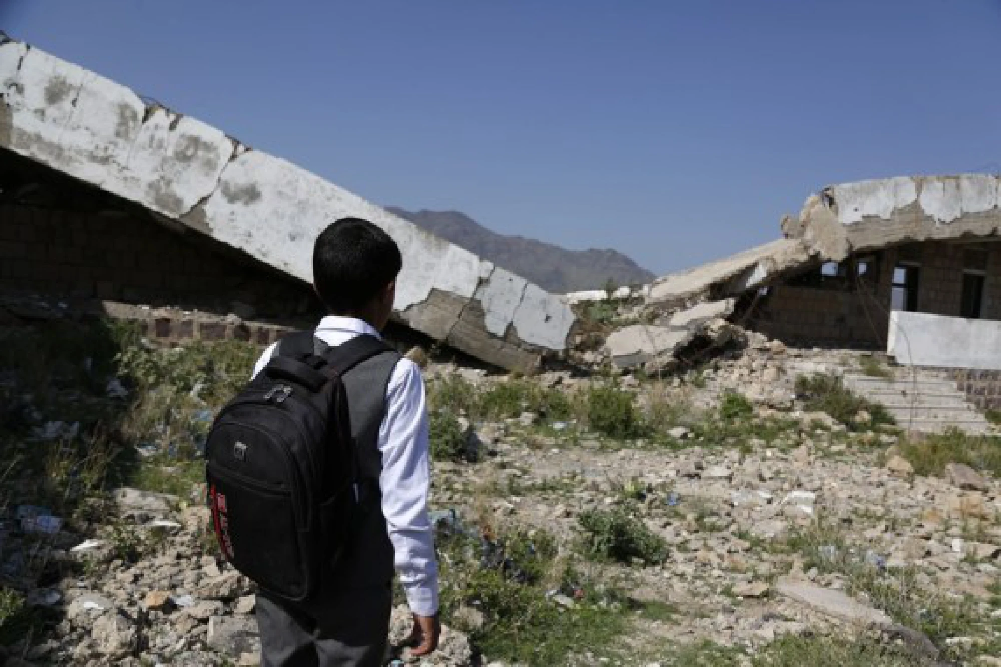 A child is standing in front of a half-collapsed teaching building at Shuhada-Alwahdah school in Al-Radhmah district in Ibb province, about 190 km south of the Houthi-held capital Sanaa, Yemen, on Aug. 14, 2021.