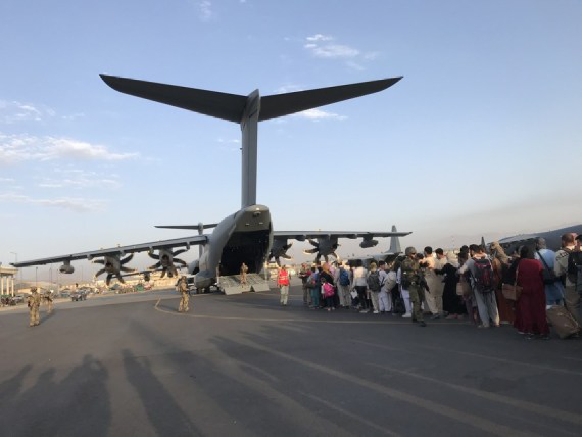People queue up to board a military aircraft of Germany and leave Kabul at Kabul airport, Afghanistan, Aug. 24, 2021.