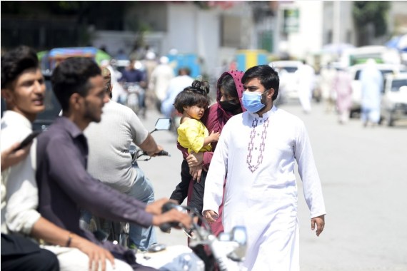 People wearing face masks walk on a road in Rawalpindi of Pakistan's Punjab Province on Aug. 2, 2021.