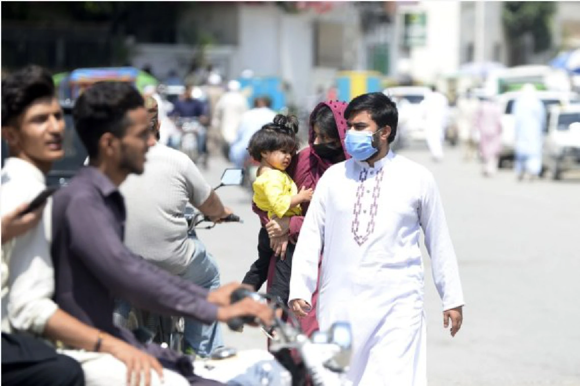 People wearing face masks walk on a road in Rawalpindi of Pakistan's Punjab Province on Aug. 2, 2021.