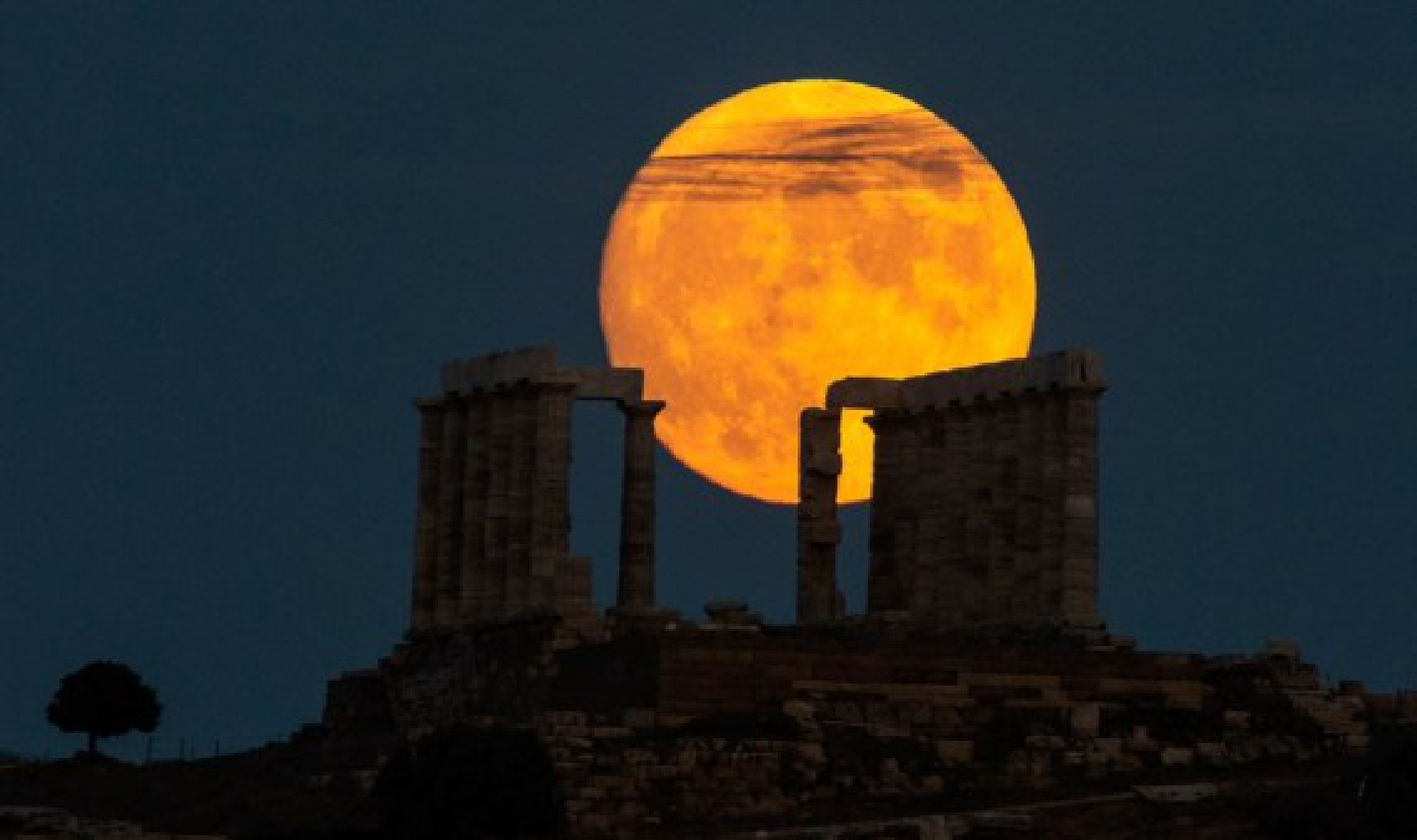 A full moon is seen over the Temple of Poseidon at cape Sounion, some 70 km southeast of Athens, Greece, on Aug. 21, 2021. 