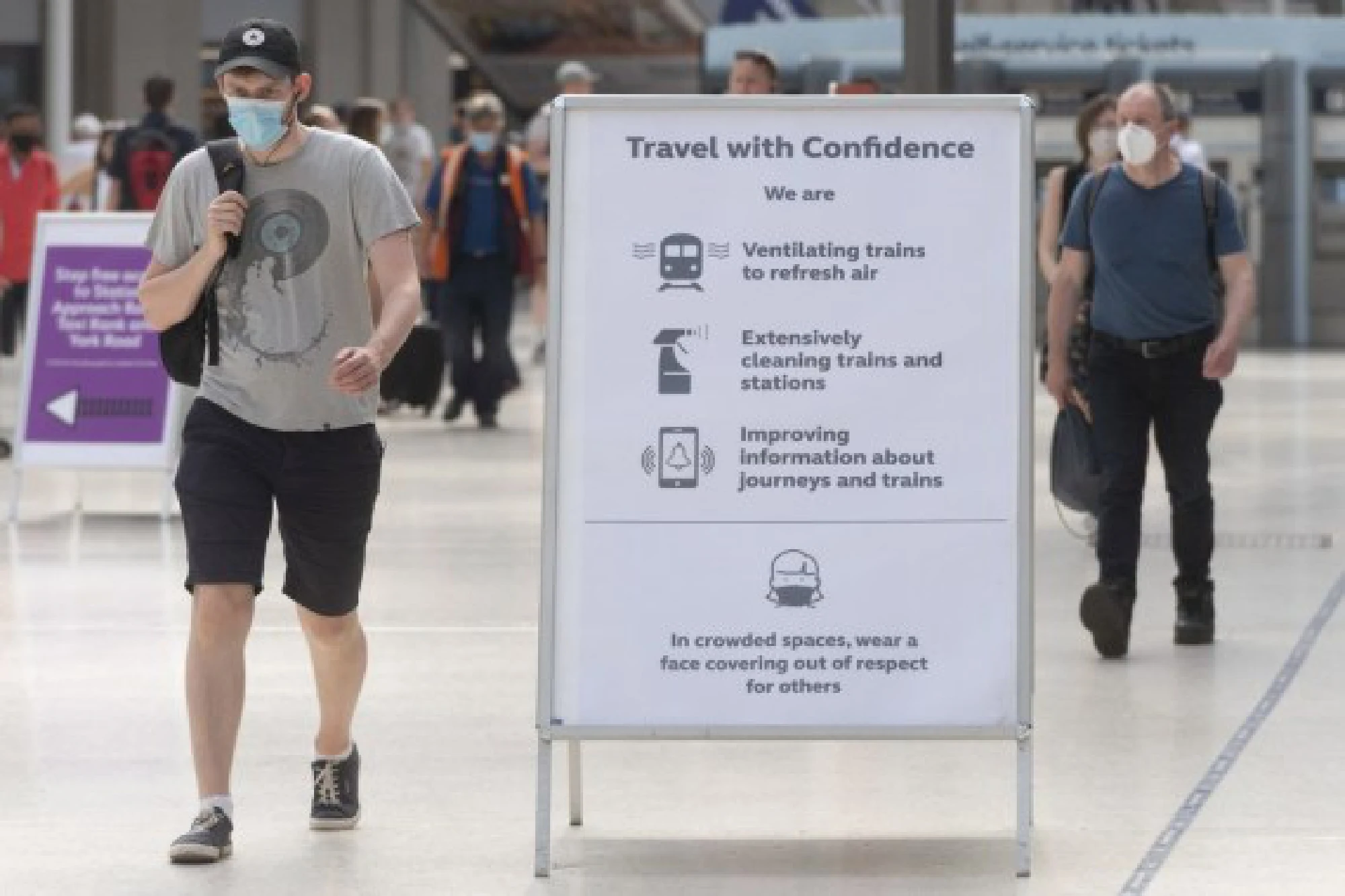  People walk past a travel safety sign at a train station in London, Britain, on July 19, 2021.