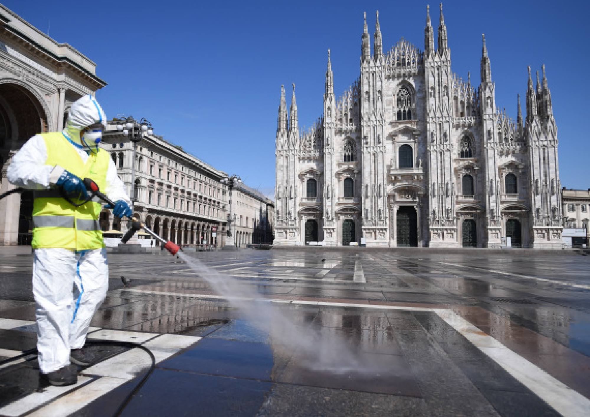A sanitation worker wearing a protective suit and a face mask cleans the ground at Piazza del Duomo in Milan, Italy, on March 31, 2020. 