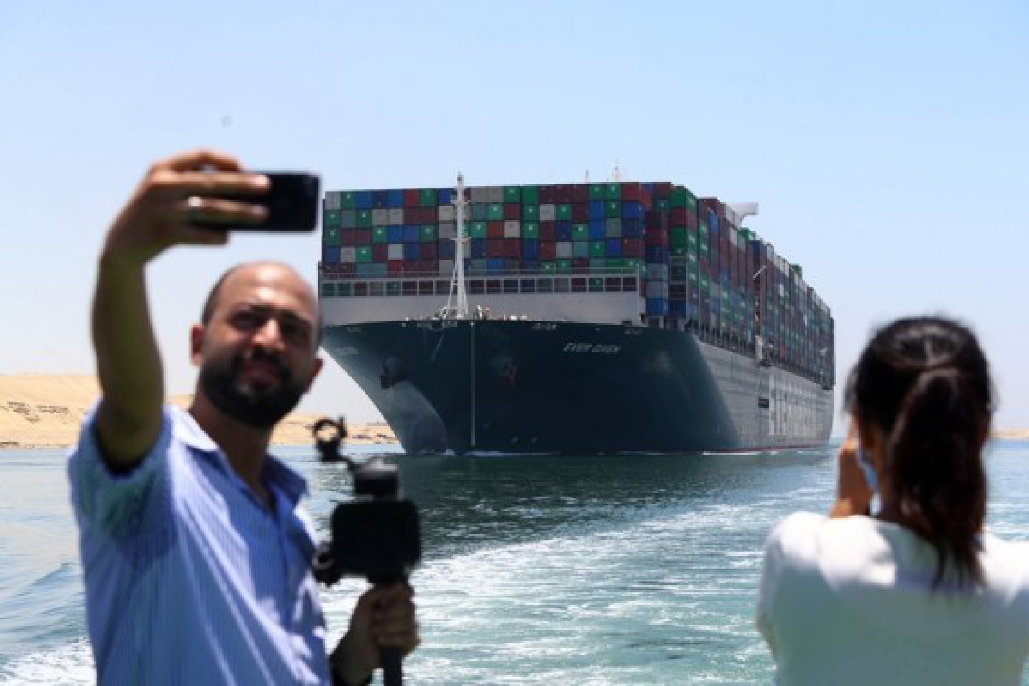 People take photos of the Ever Given container ship sailing on the Suez Canal in Ismailia Province, Egypt, July 7, 2021. 