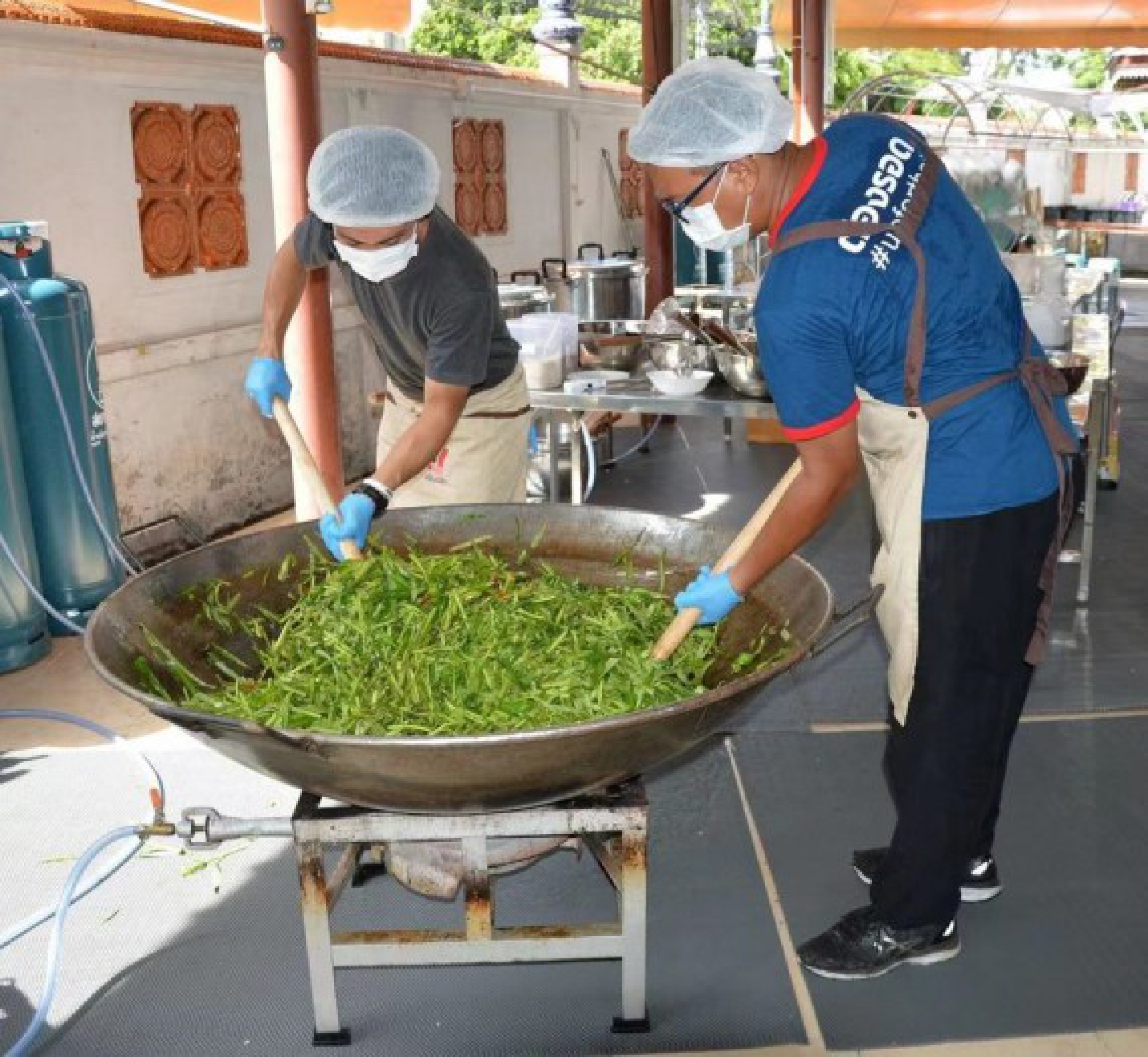 Photo taken on June 8, 2021 shows two volunteers of Up for Thai cooking vegetables in a temporary kitchen set up in a temple in northern Bangkok, Thailand.