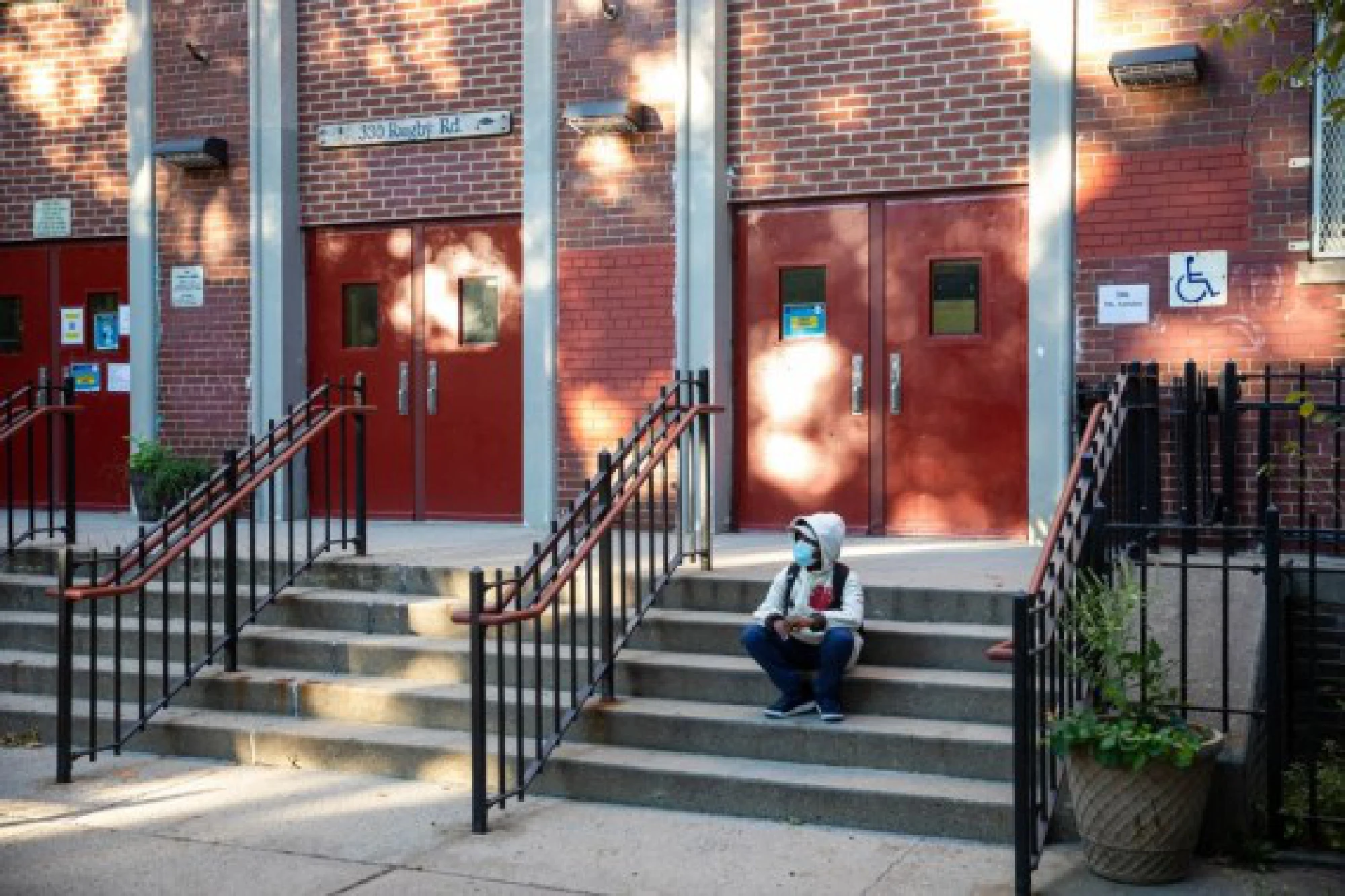 A student is seen on the steps of the closed public school PS 139 in the Ditmas Park neighborhood in Brooklyn of New York, the United States, Oct. 8, 2020.