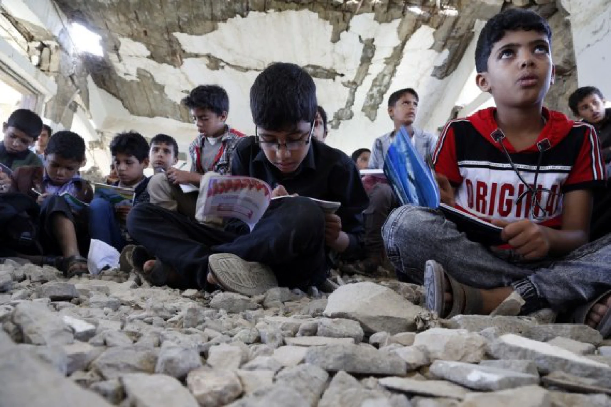 School children sit on the ground inside a half-collapsed teaching building at Alwahdah school in Al-Radhmah district in Ibb province, about 190 km south of the Houthi-held capital Sanaa, Yemen, on Aug. 14, 2021. 