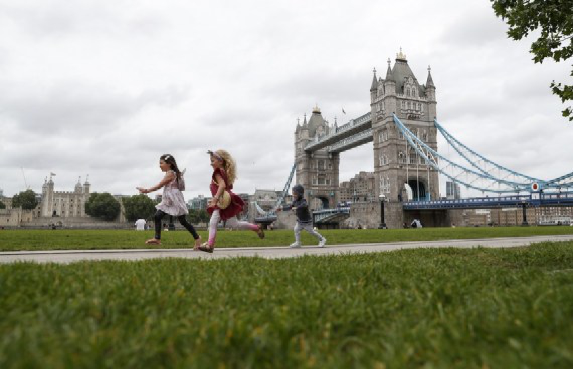 Children run in front of the Tower Bridge in London, Britain, on Aug. 13, 2021.