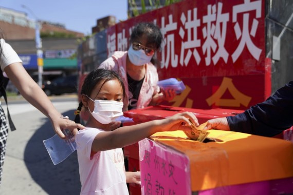 A girl donates money to help flood-hit people in central China's Henan province to restore life and production, in New York, the United States, July 31, 2021.