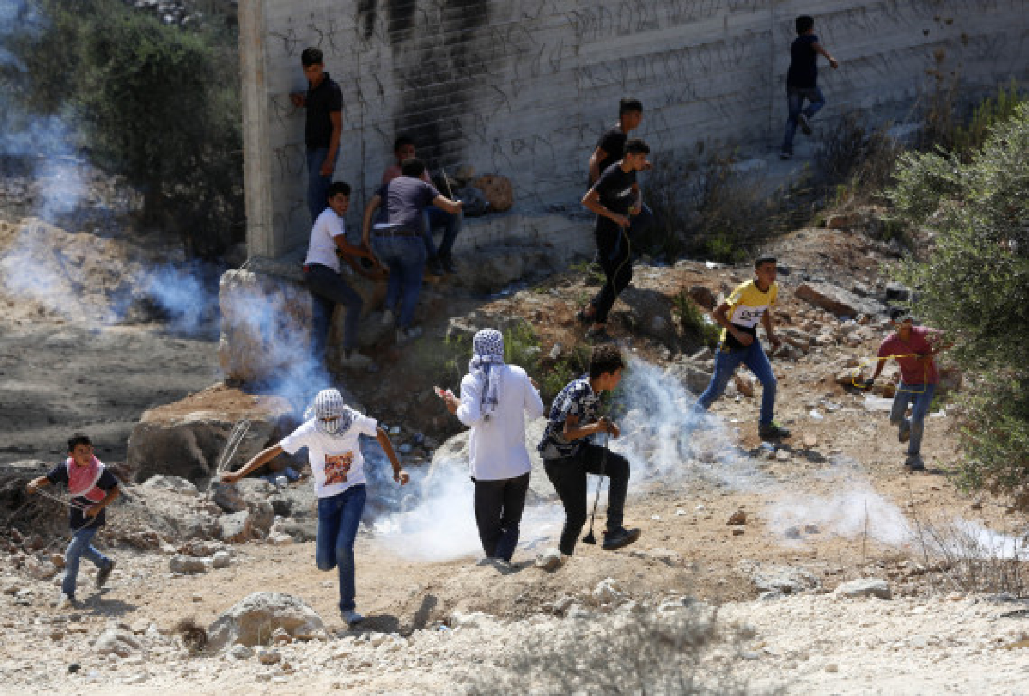 Protesters run to take cover from tear gas canister during clashes with Israeli soldiers in the village of Beita, south of the West Bank city of Nablus, Aug 20, 2021. 