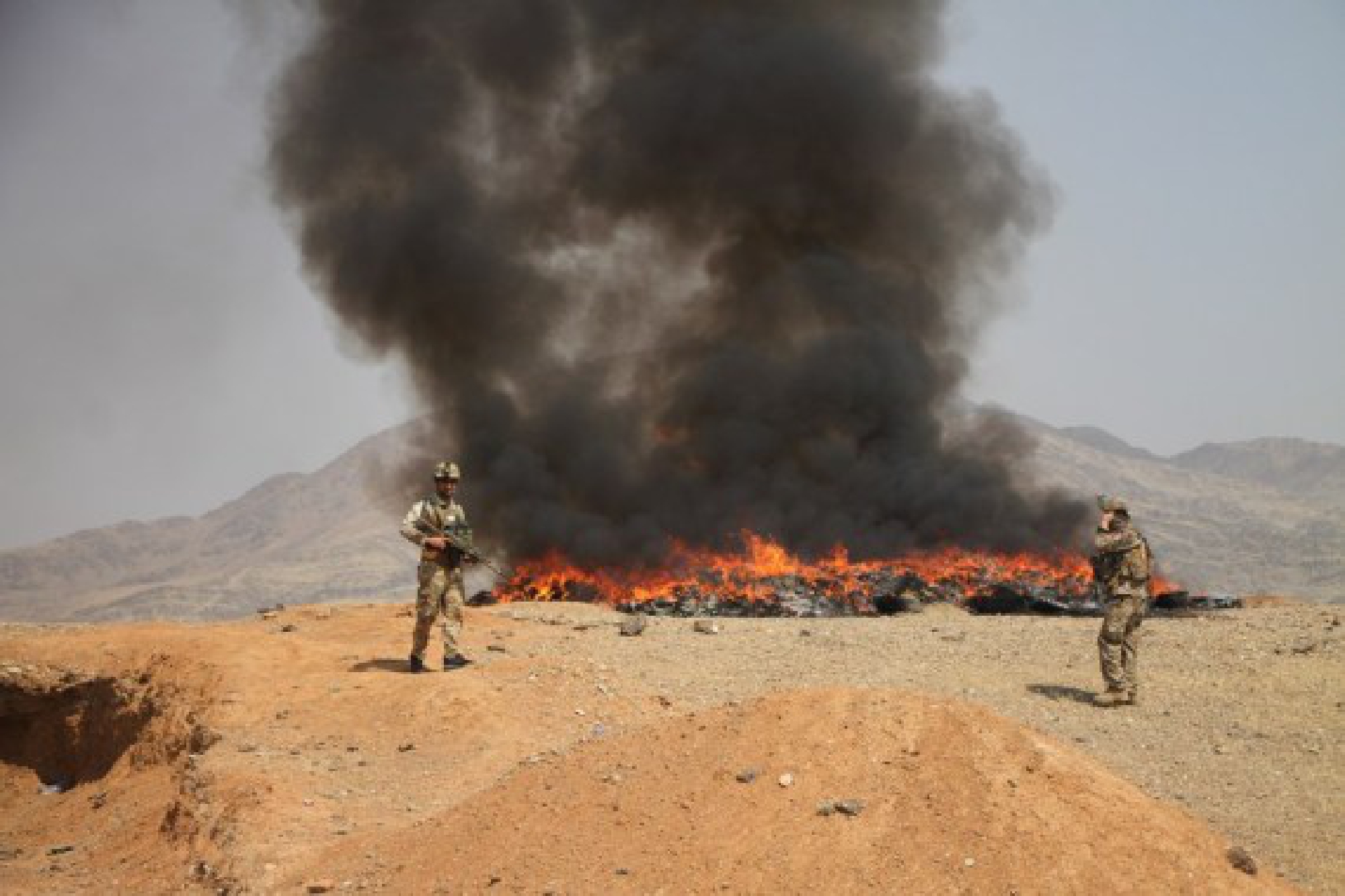 Afghan security force members are seen near the burning drugs in Jalalabad, Nangarhar Province, Afghanistan, Aug. 11, 2021. 
