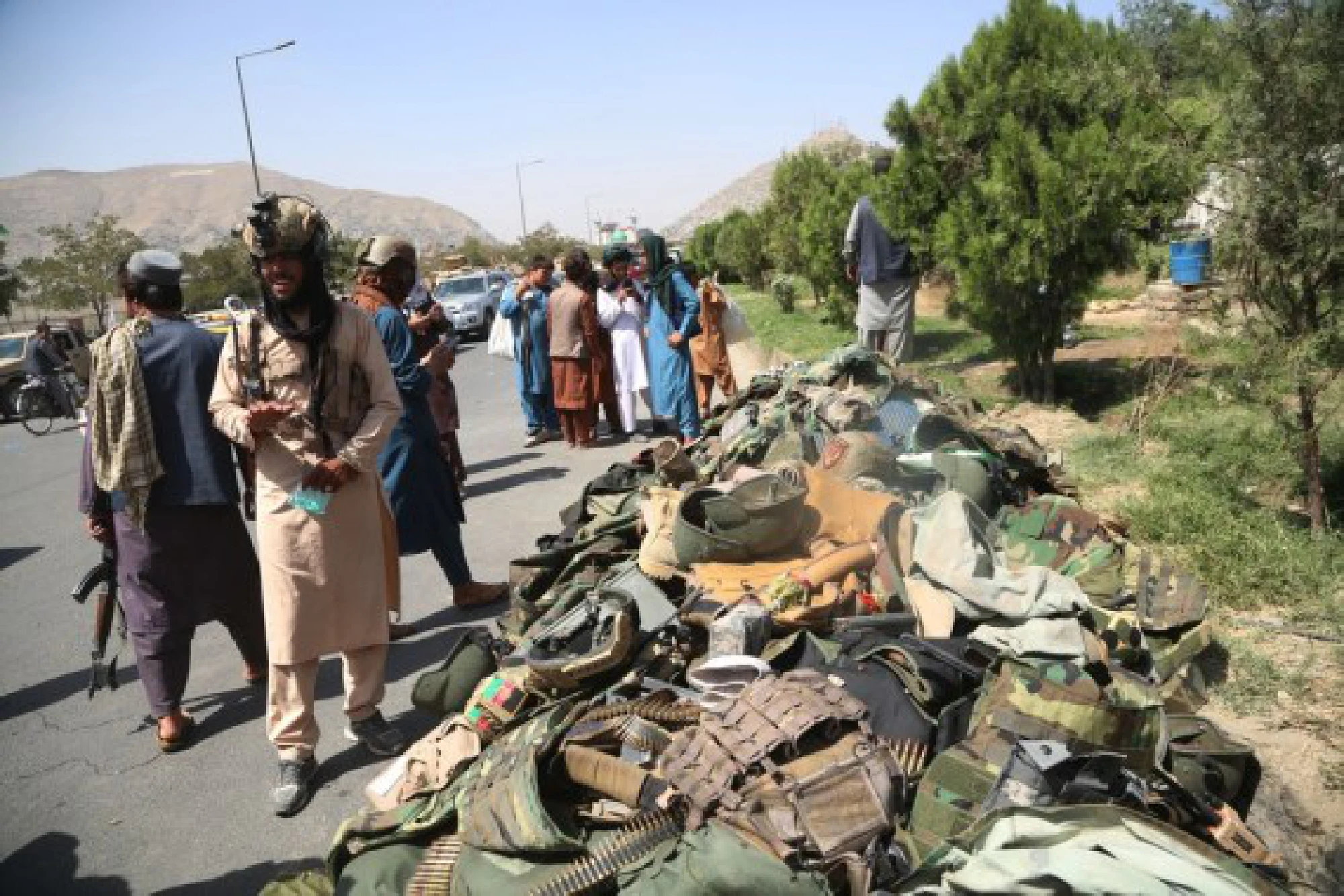 Taliban fighters stand beside the belongings of Afghan security soldiers in Kabul, capital of Afghanistan, Aug. 16, 2021.