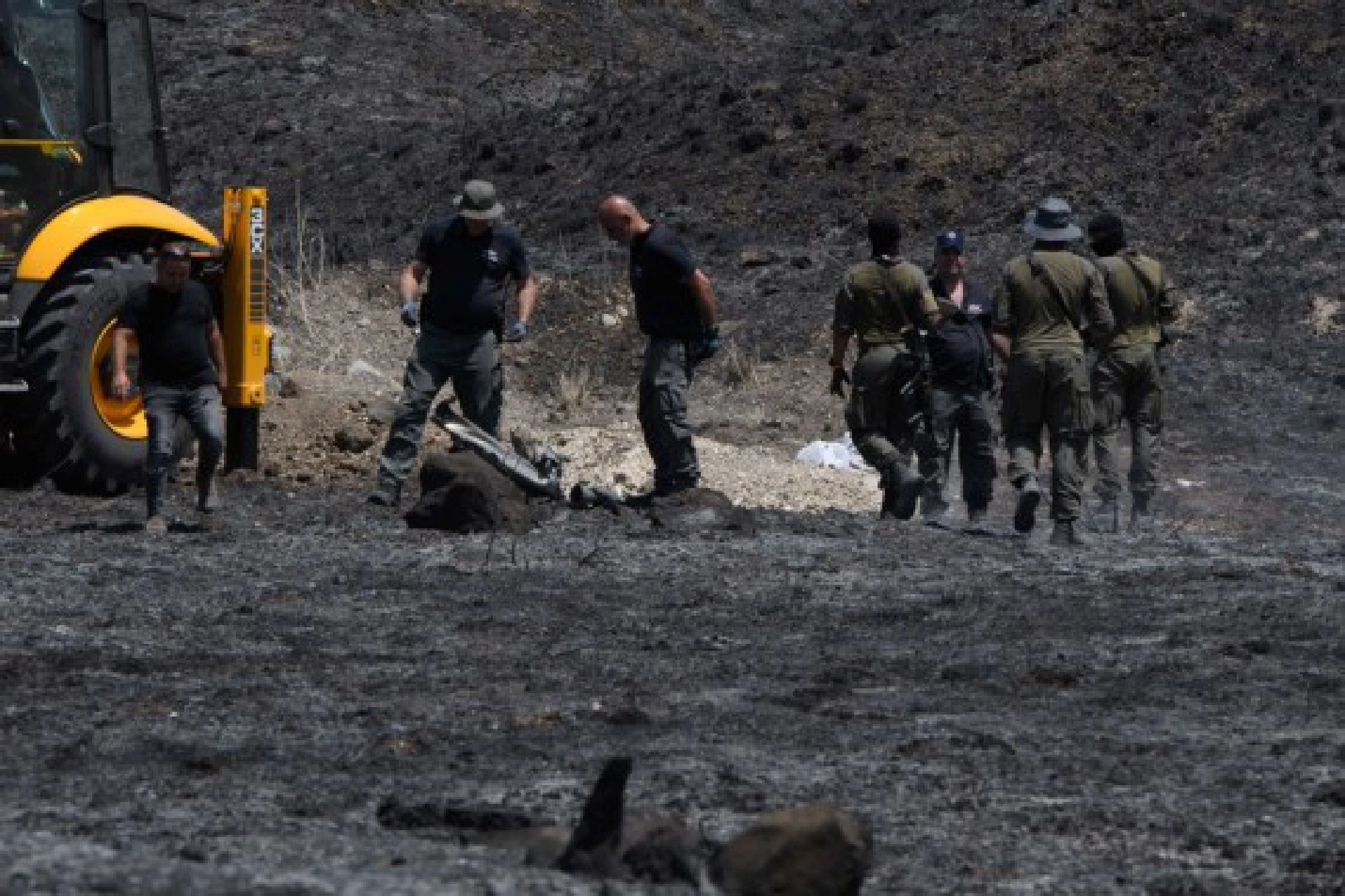 Israeli security members deal with the wreckage of a rocket launched from Lebanon into northern Israel, near the city of Kiryat Shmona, on Aug. 4, 2021. 