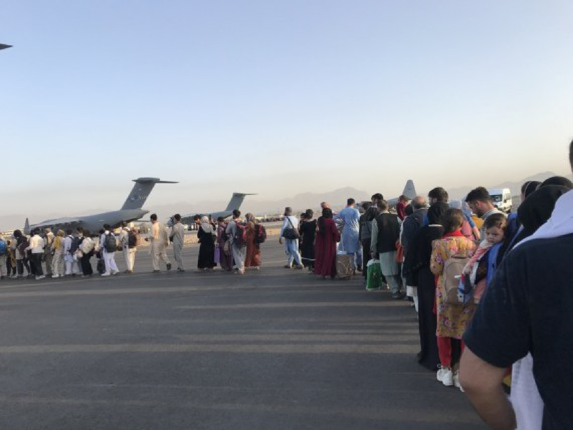 People queue up to board a military aircraft of Germany and leave Kabul at Kabul airport, Afghanistan, Aug. 24, 2021. 
