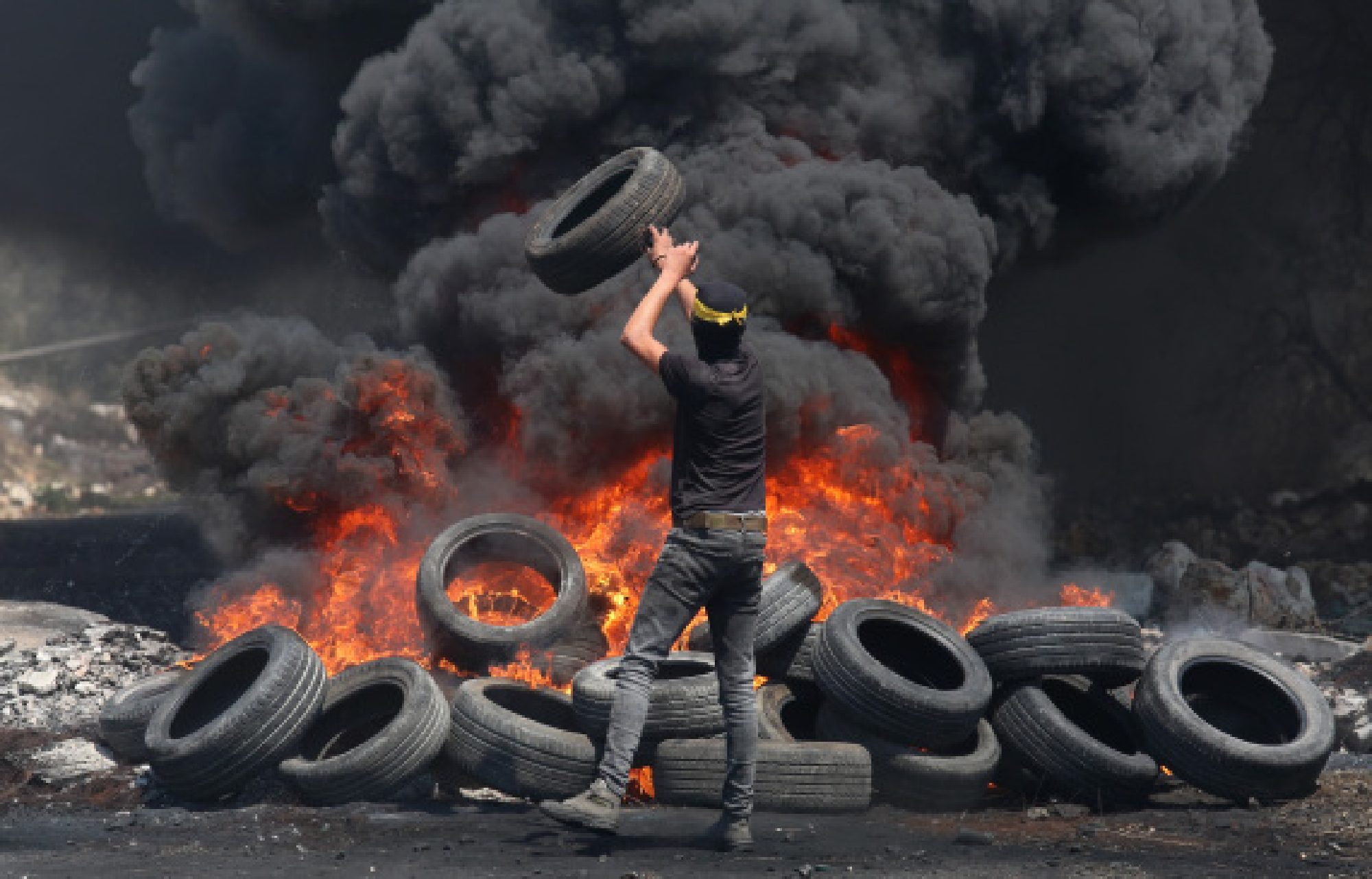 Palestinian protester burns tires during clashes with Israeli soldiers after a protest against the expanding of Jewish settlements in Kufr Qadoom village near the West Bank city of Nablus, Aug. 20, 2021. 
