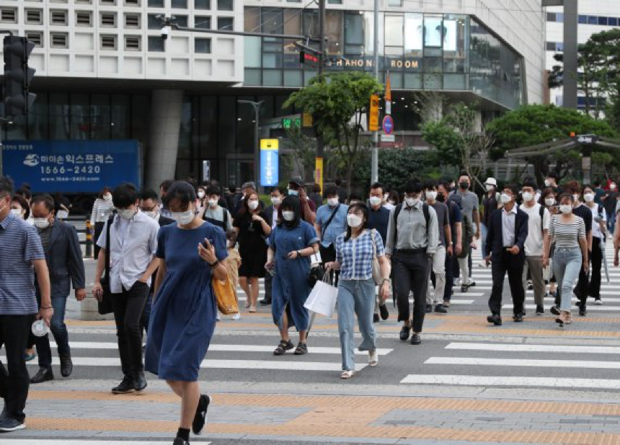 People wearing face masks walk across the street near Yongsan Station in Seoul, South Korea, July 8, 2021.