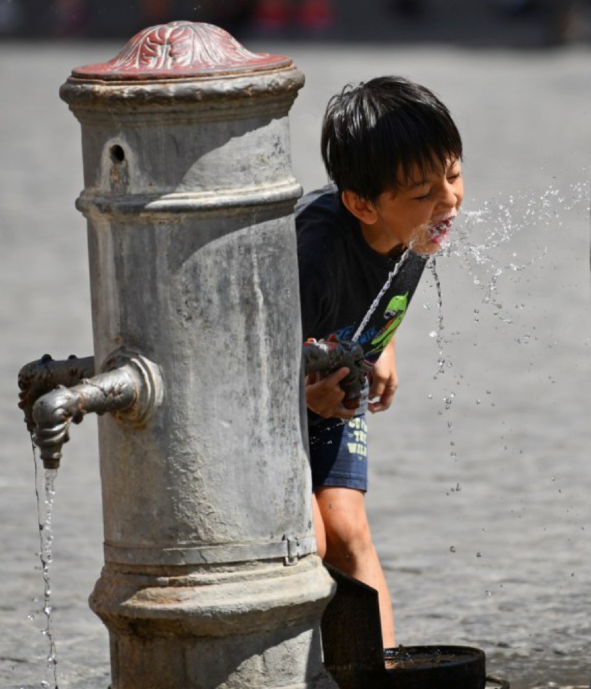 A boy refreshes himself with the tap water in Rome, Italy, Aug. 12, 2021.