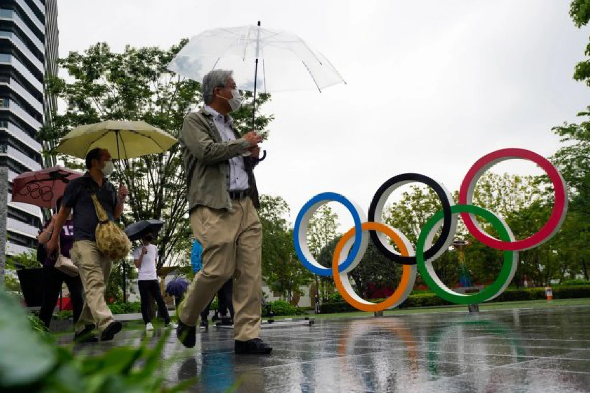People walk past the Olympic Rings near the new National Stadium in Tokyo, Japan on July 8, 2021.
